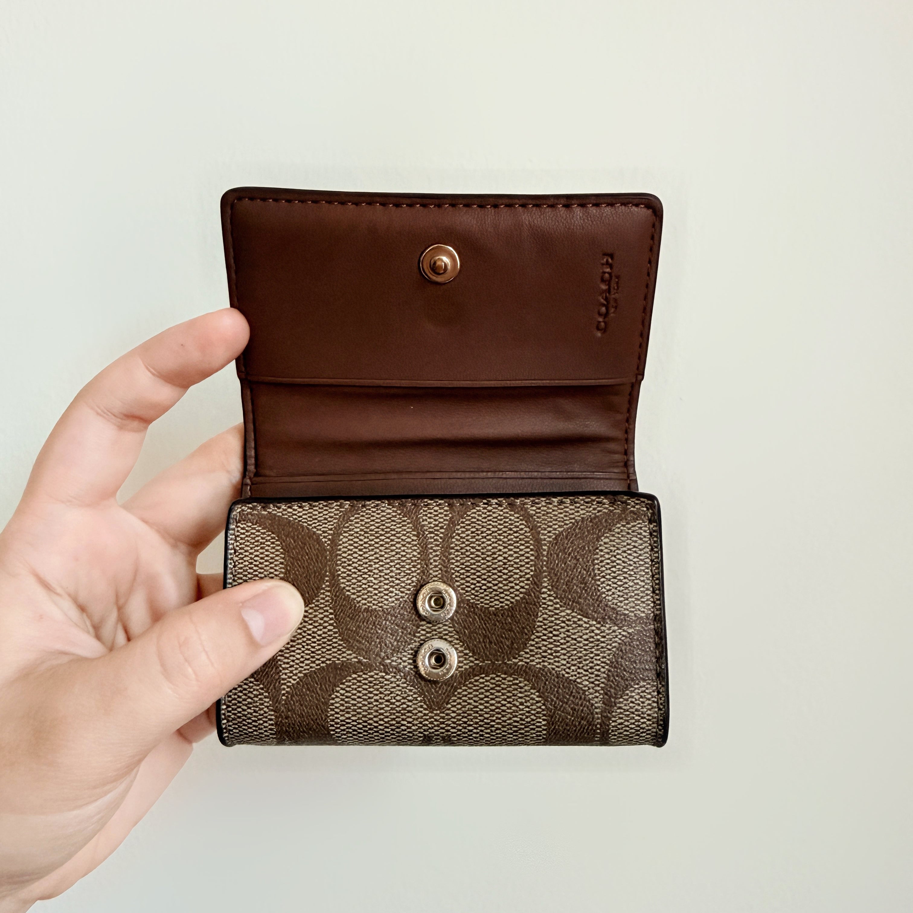 Coach Signature Canvas Key Case in beige with gold-tone logo and signature monogram pattern, shown in a front view.