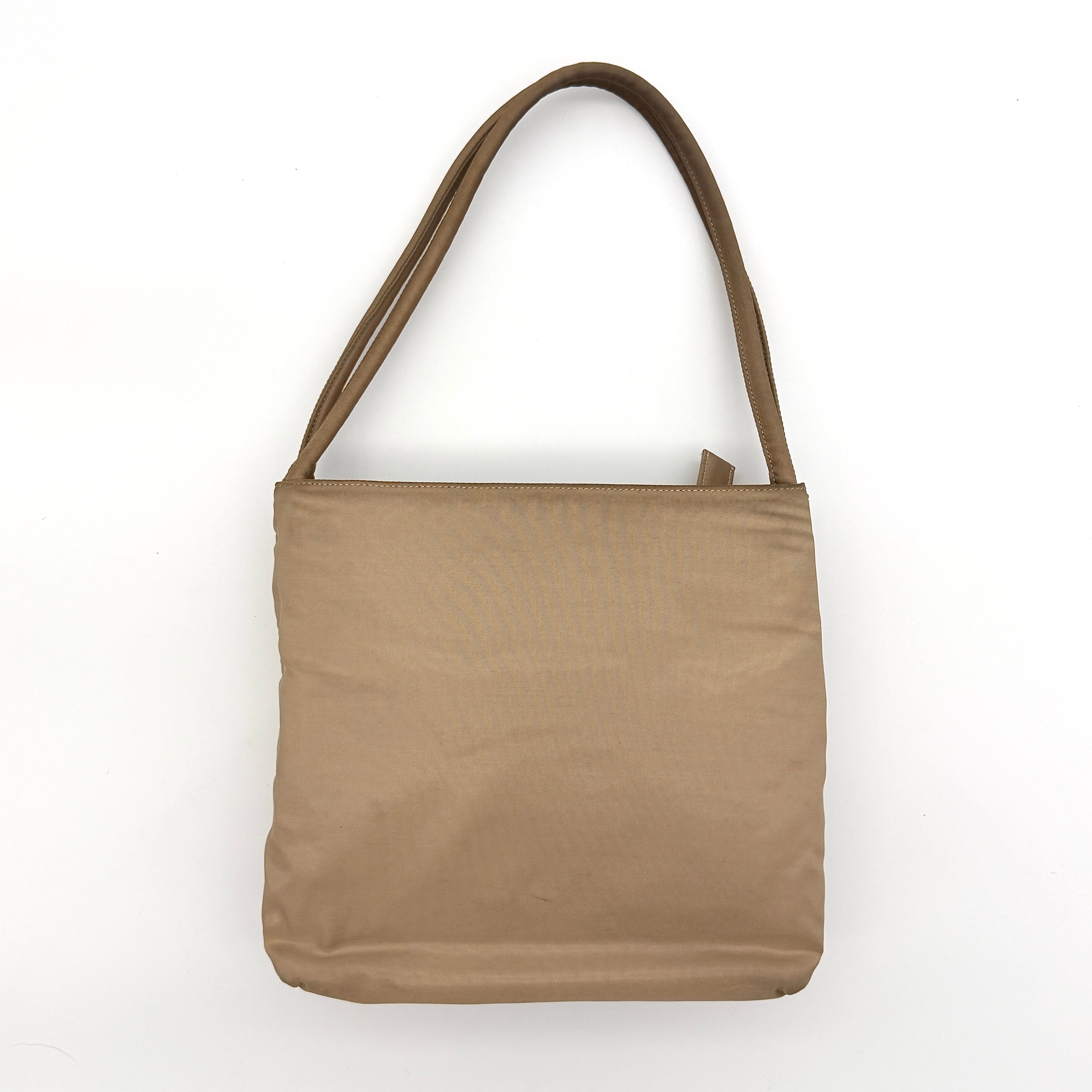 Prada Tessuto nylon tote bag in beige with silver-tone logo plaque and dual handles.