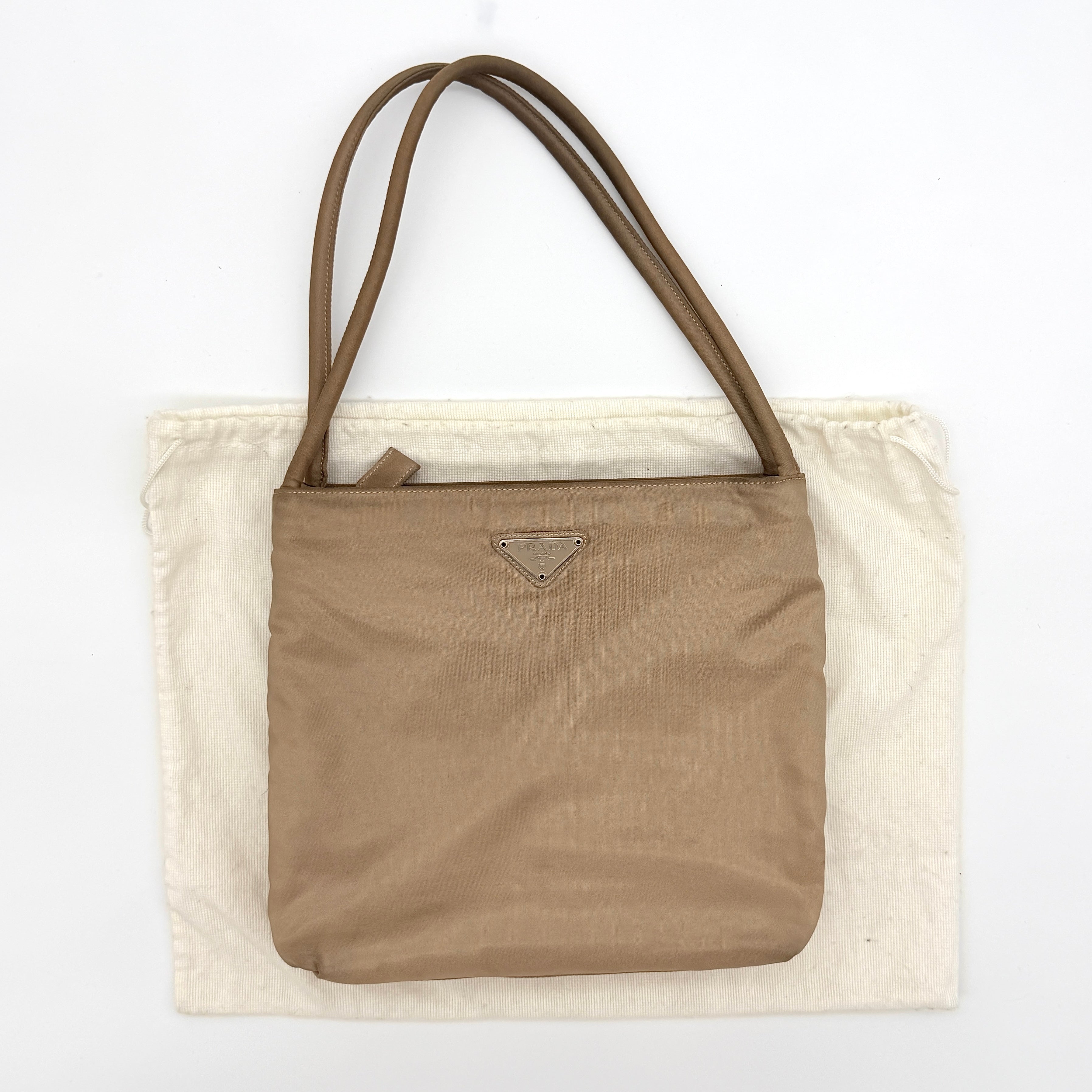 Prada Tessuto nylon tote bag in beige with silver-tone logo plaque and dual handles.