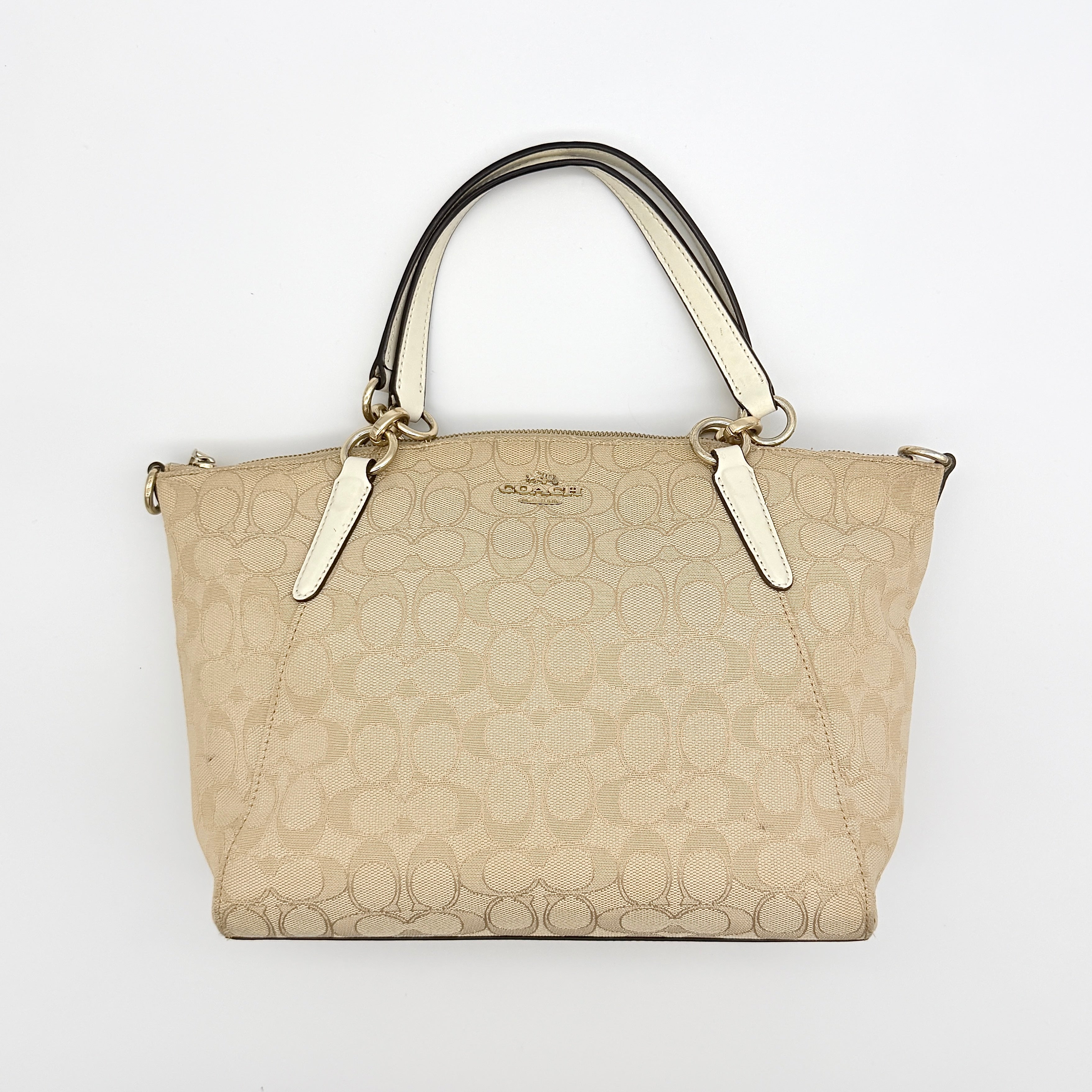 Coach Kelsey 2Way shoulder bag in beige signature canvas with cream leather handles and detachable strap, shown on a white background.
