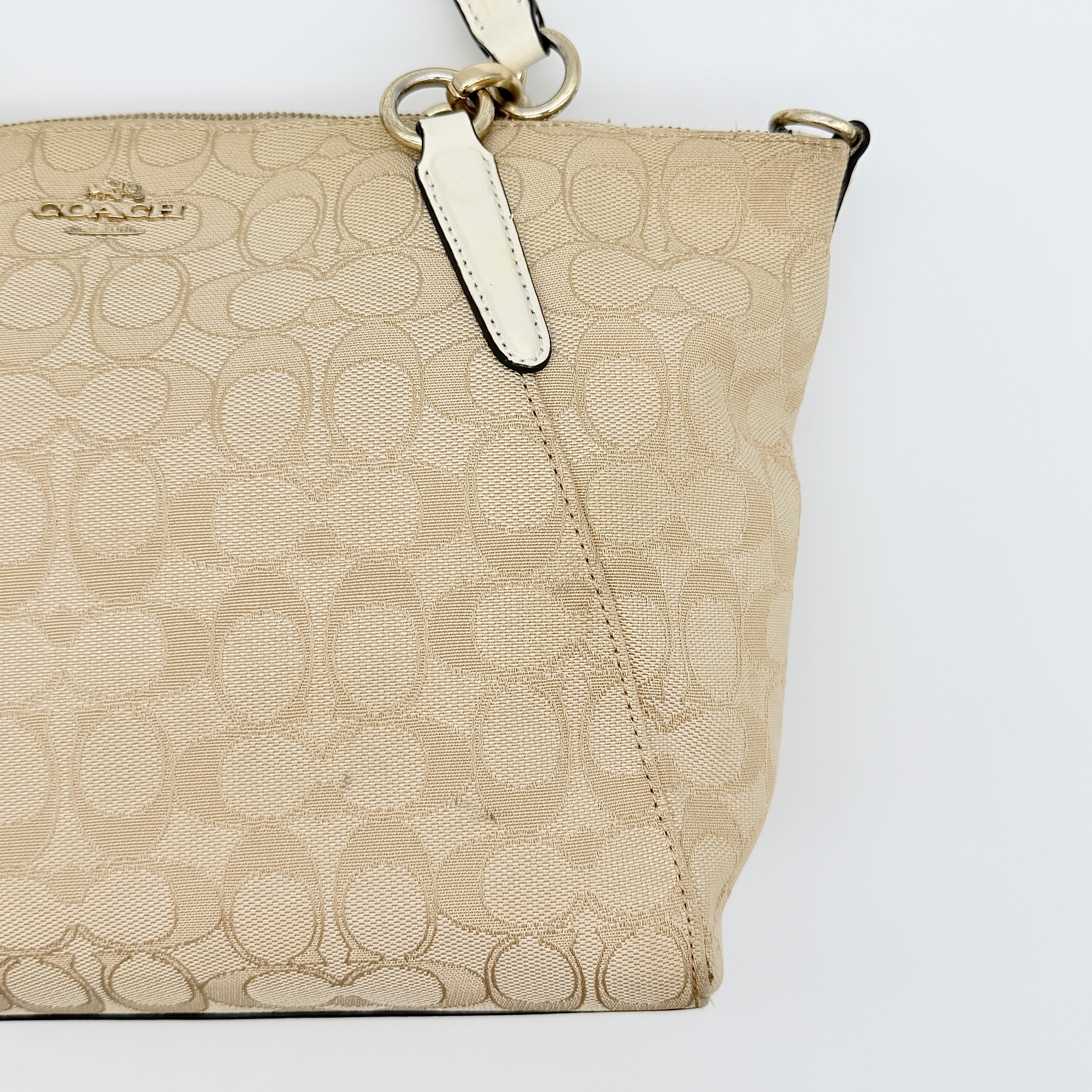 Coach Kelsey 2Way shoulder bag in beige signature canvas with cream leather handles and detachable strap, shown on a white background.