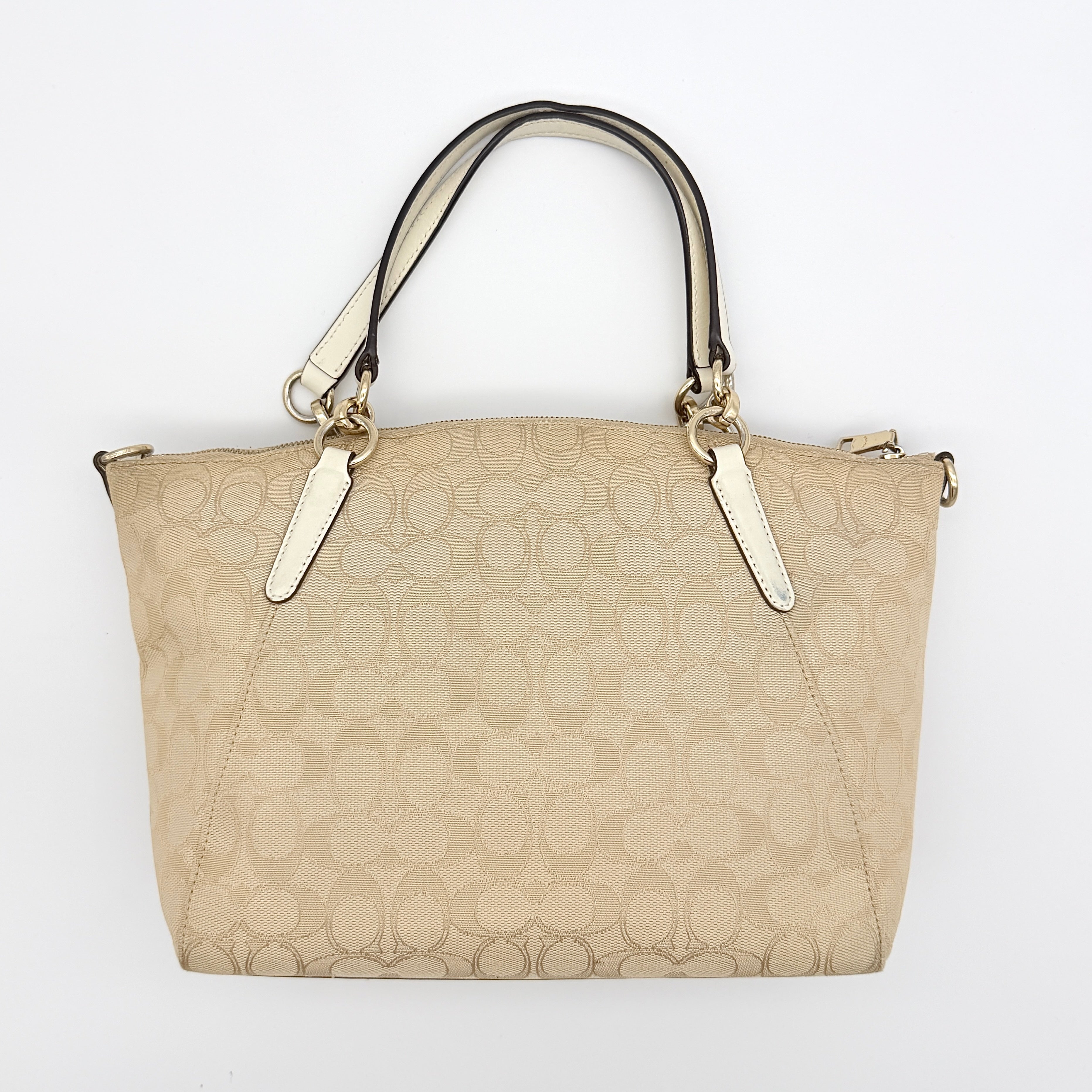 Coach Kelsey 2Way shoulder bag in beige signature canvas with cream leather handles and detachable strap, shown on a white background.