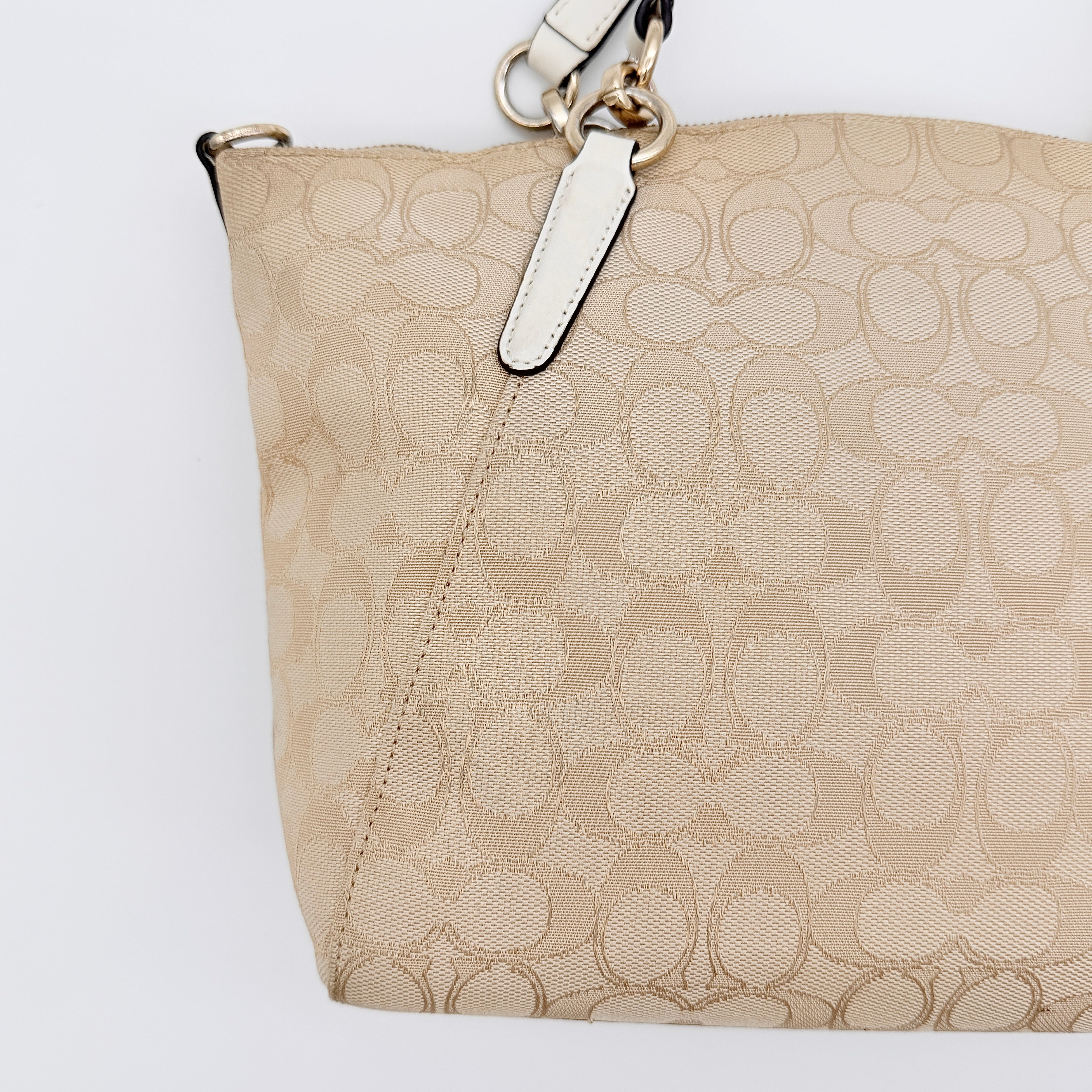 Coach Kelsey 2Way shoulder bag in beige signature canvas with cream leather handles and detachable strap, shown on a white background.