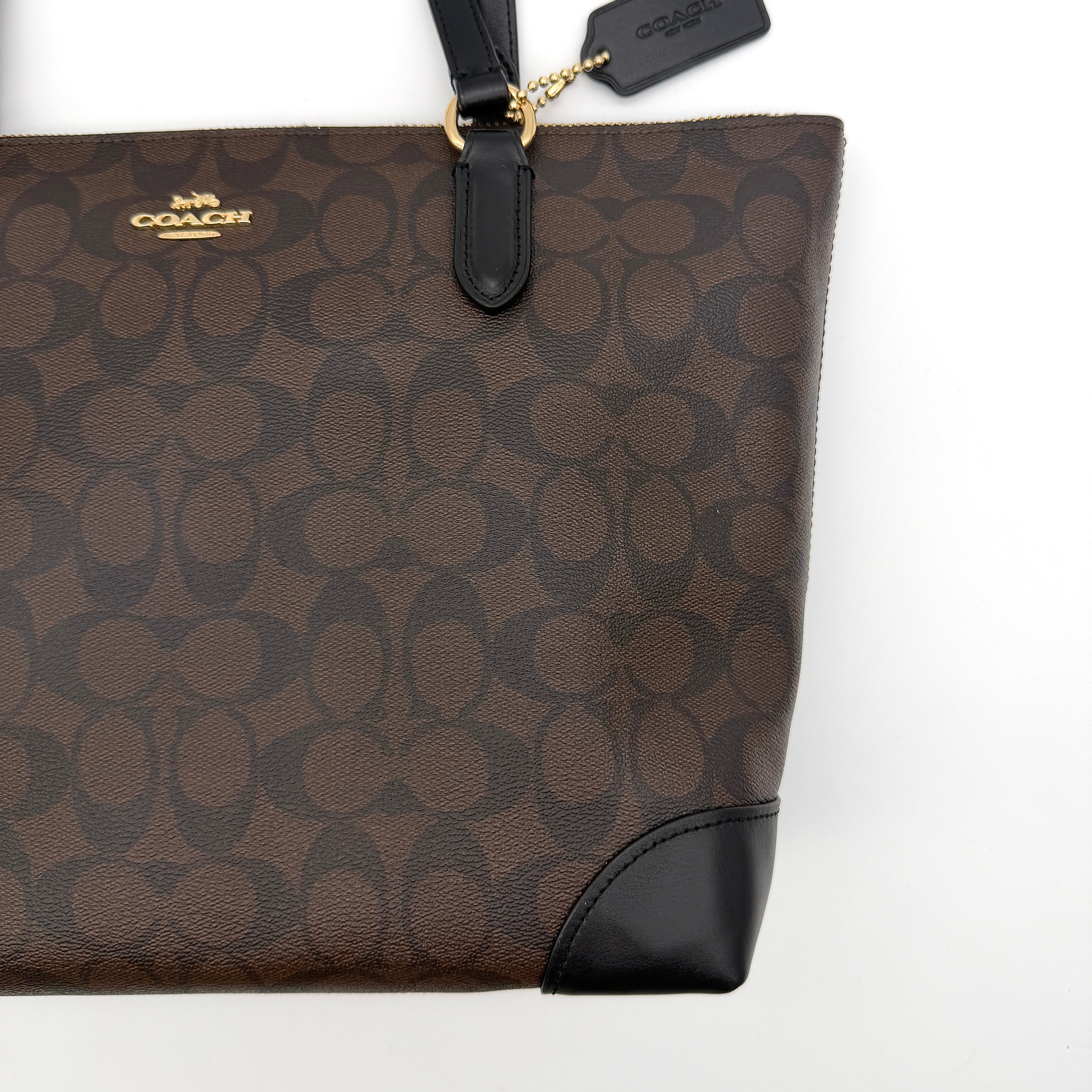Coach Signature Zip Top Tote Bag in brown and black canvas with leather trim and gold-tone hardware.