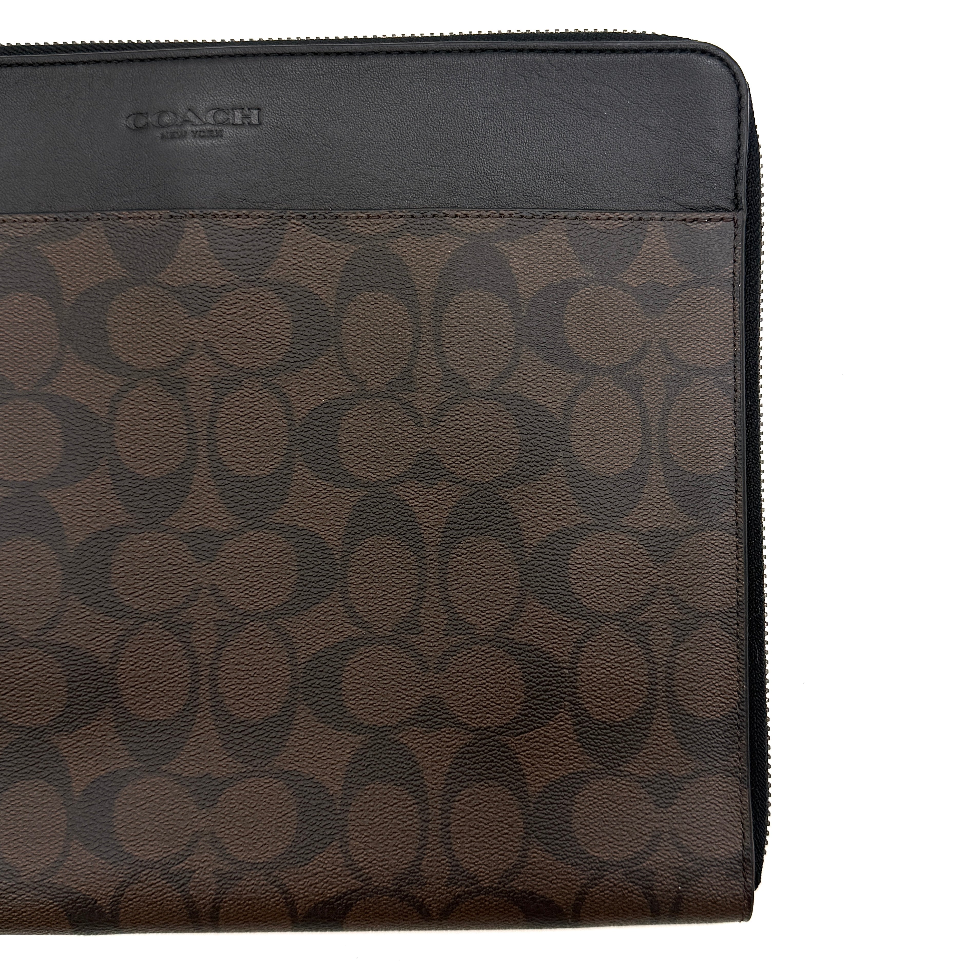 Coach Signature Zip Portfolio in brown and black monogram canvas with zip-around closure, displayed flat against a white background.