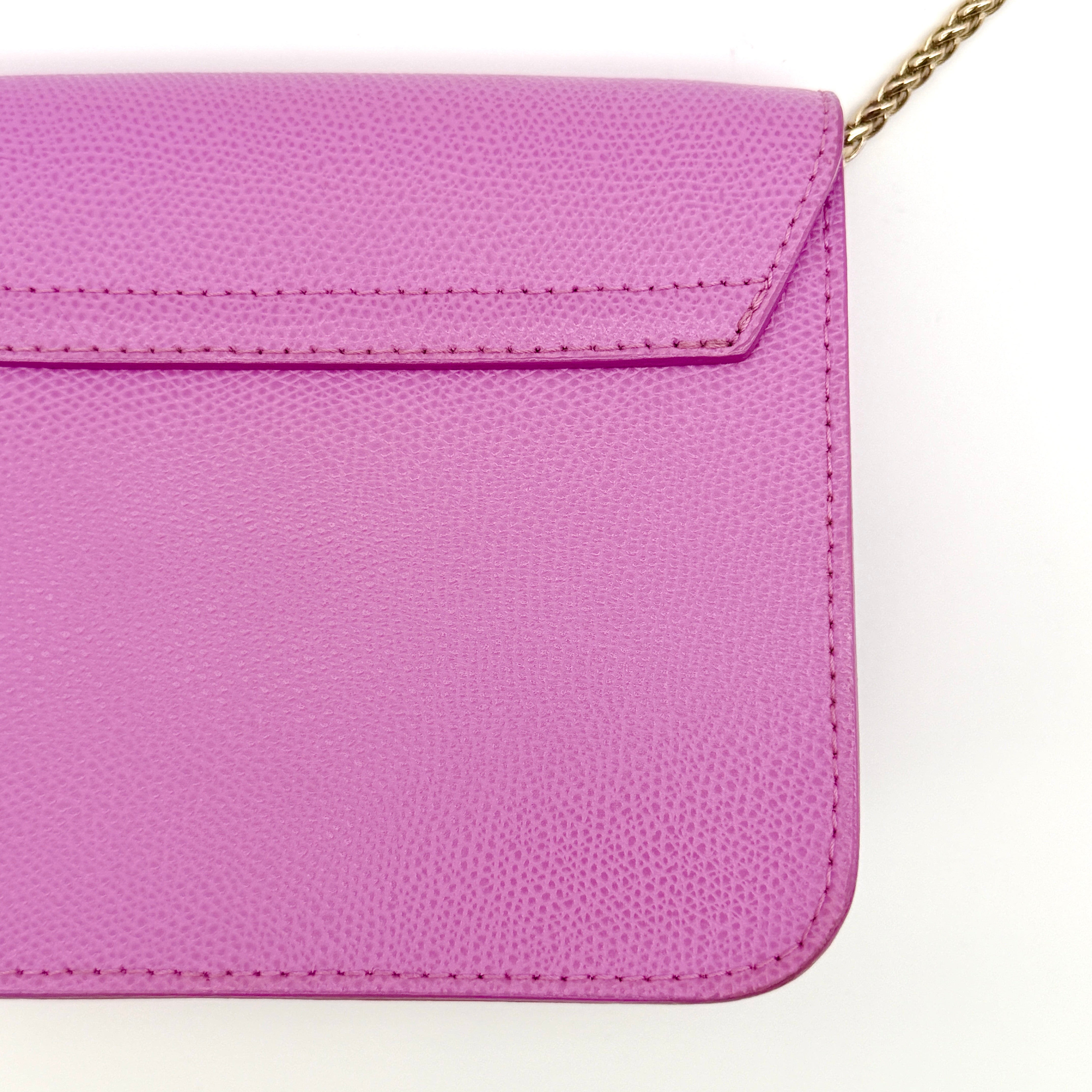 Furla Metropolis crossbody bag in pink grained leather with gold hardware and chain strap, displayed against a white background.