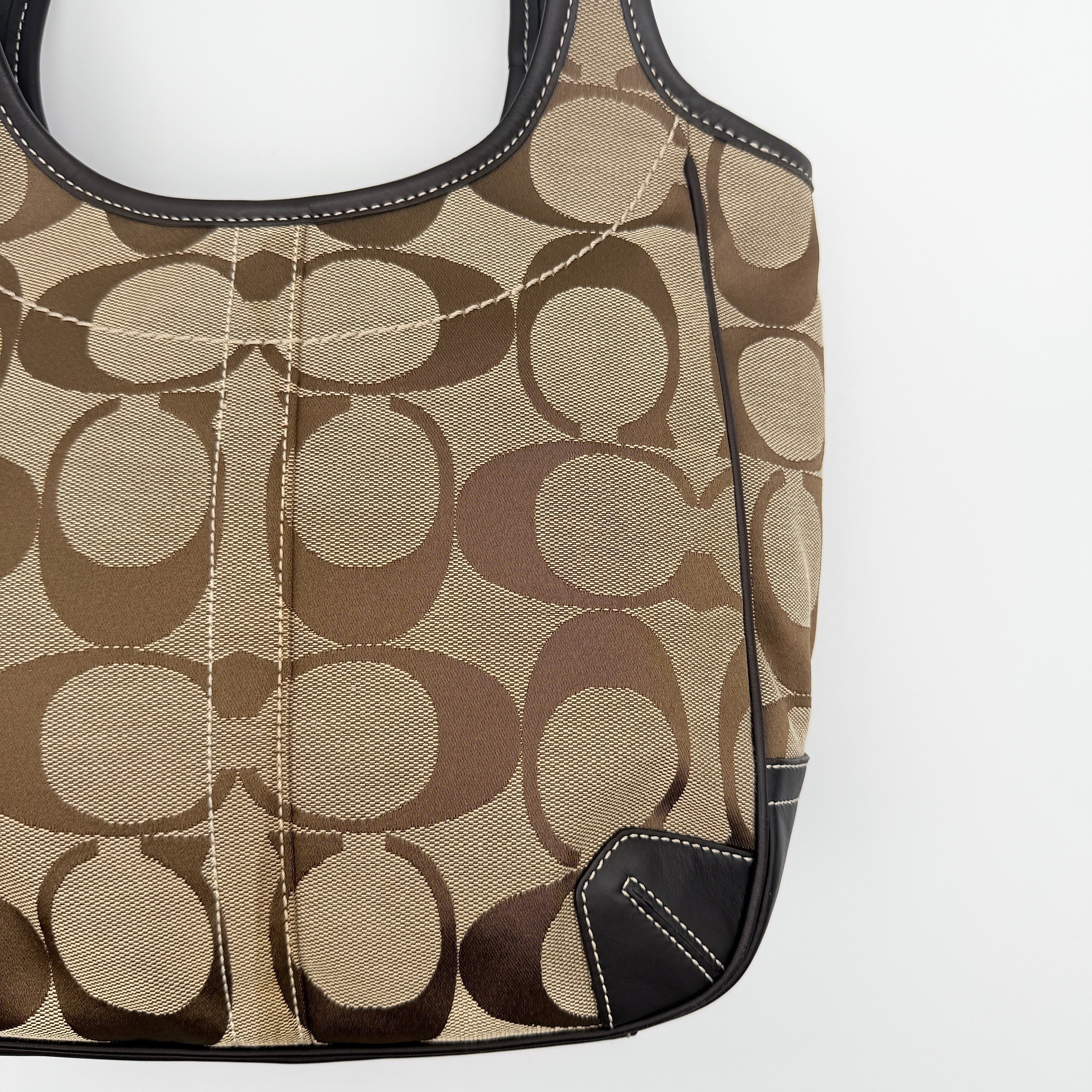 Coach Signature Ergo Hobo Tote Bag in beige and brown canvas with front pocket and dark leather trim, shown on a white background.