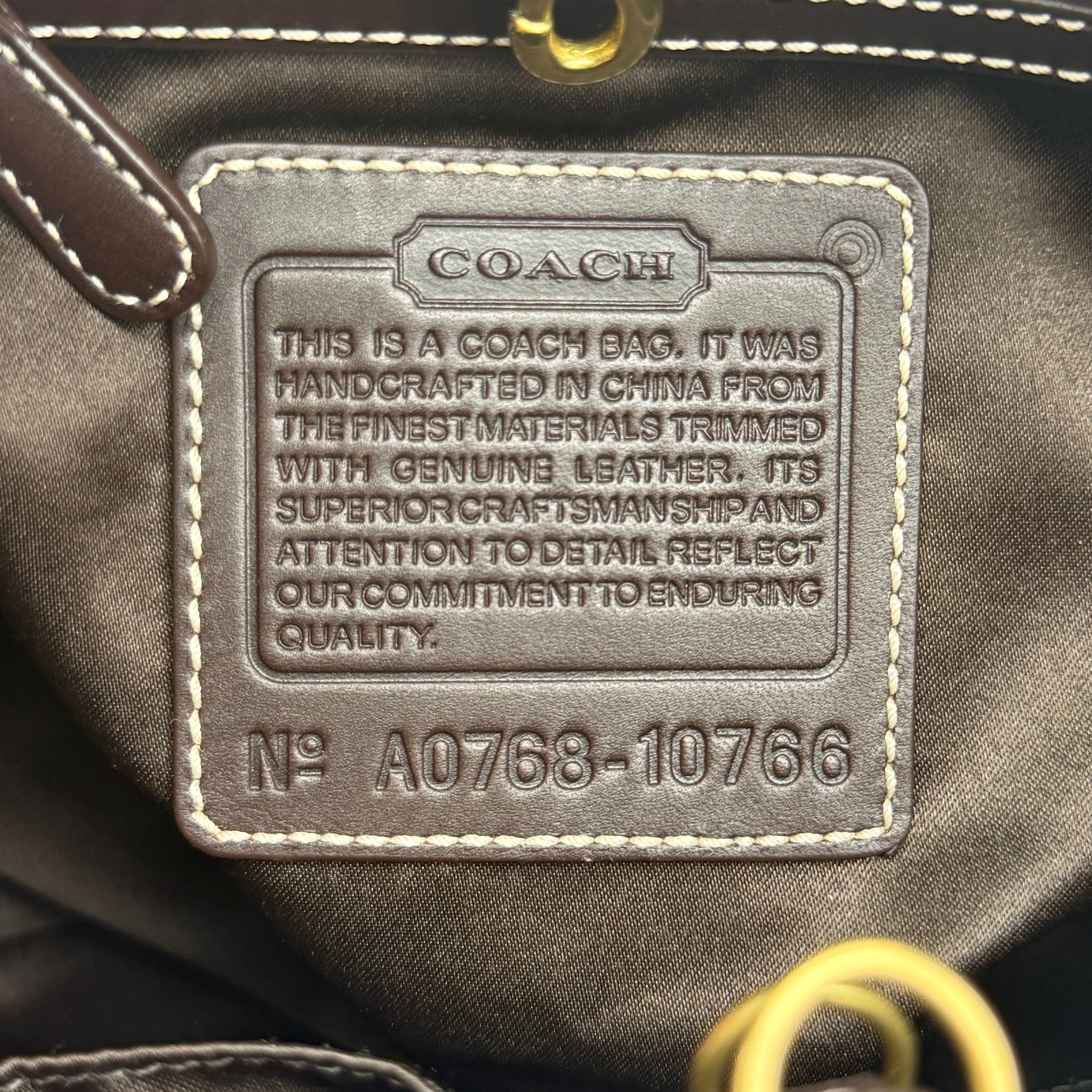 Coach Signature Ergo Hobo Tote Bag in beige and brown canvas with front pocket and dark leather trim, shown on a white background.