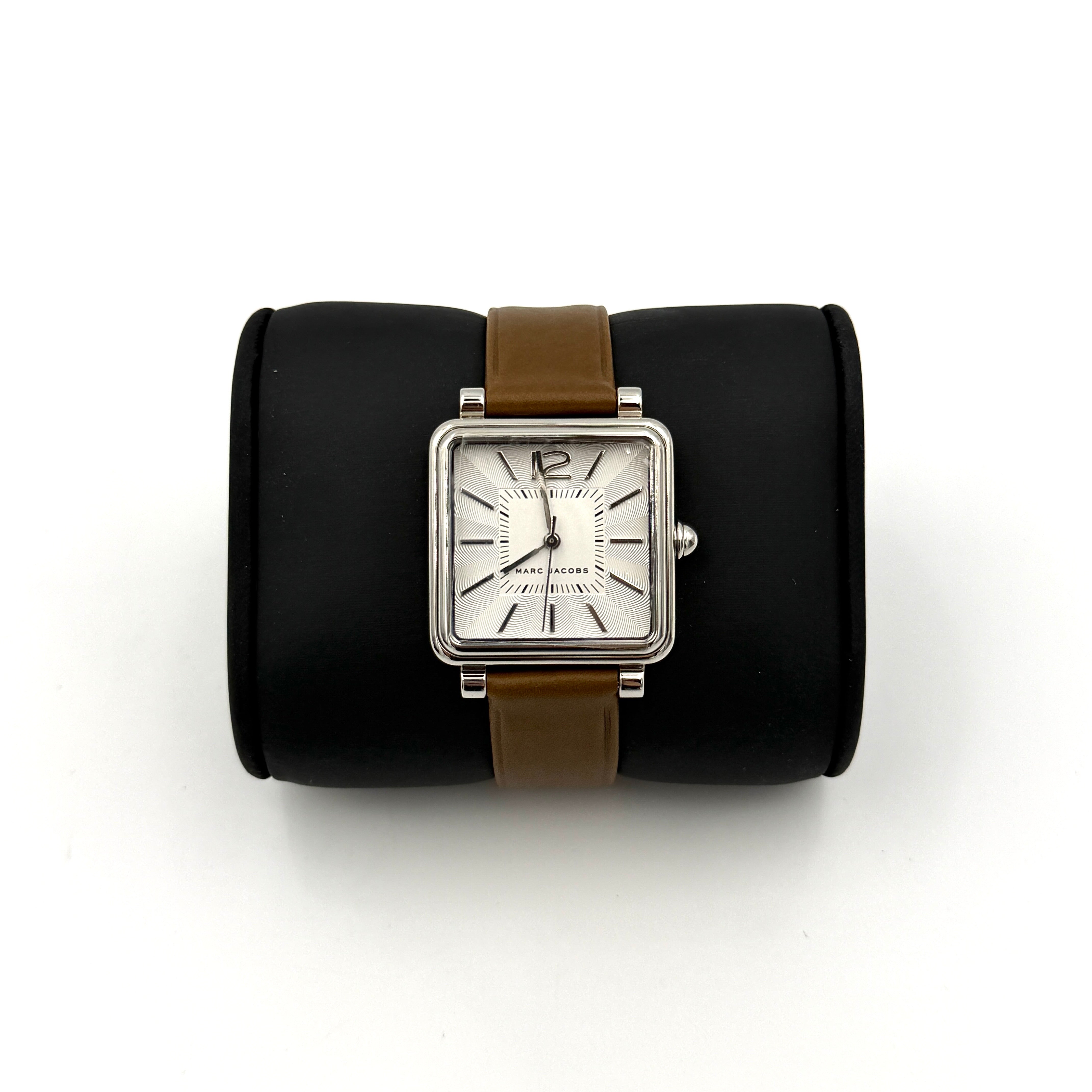 Marc Jacobs MJ1436 silver square watch with brown leather strap displayed on a branded watch cushion.