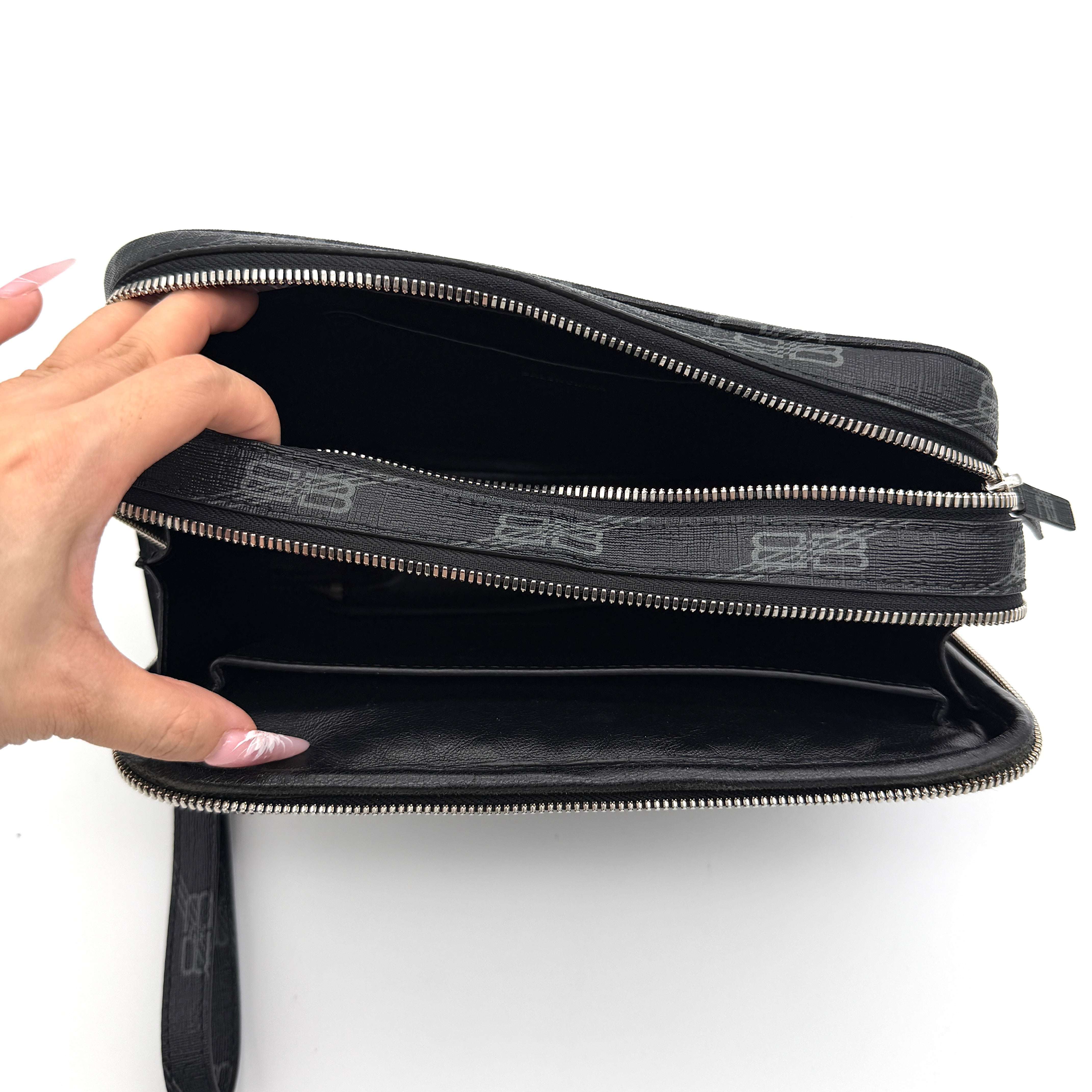 Balenciaga Signature BB Monogram Everyday Clutch Bag in black with double zip compartments and detachable wrist strap displayed on a Balenciaga dust bag.