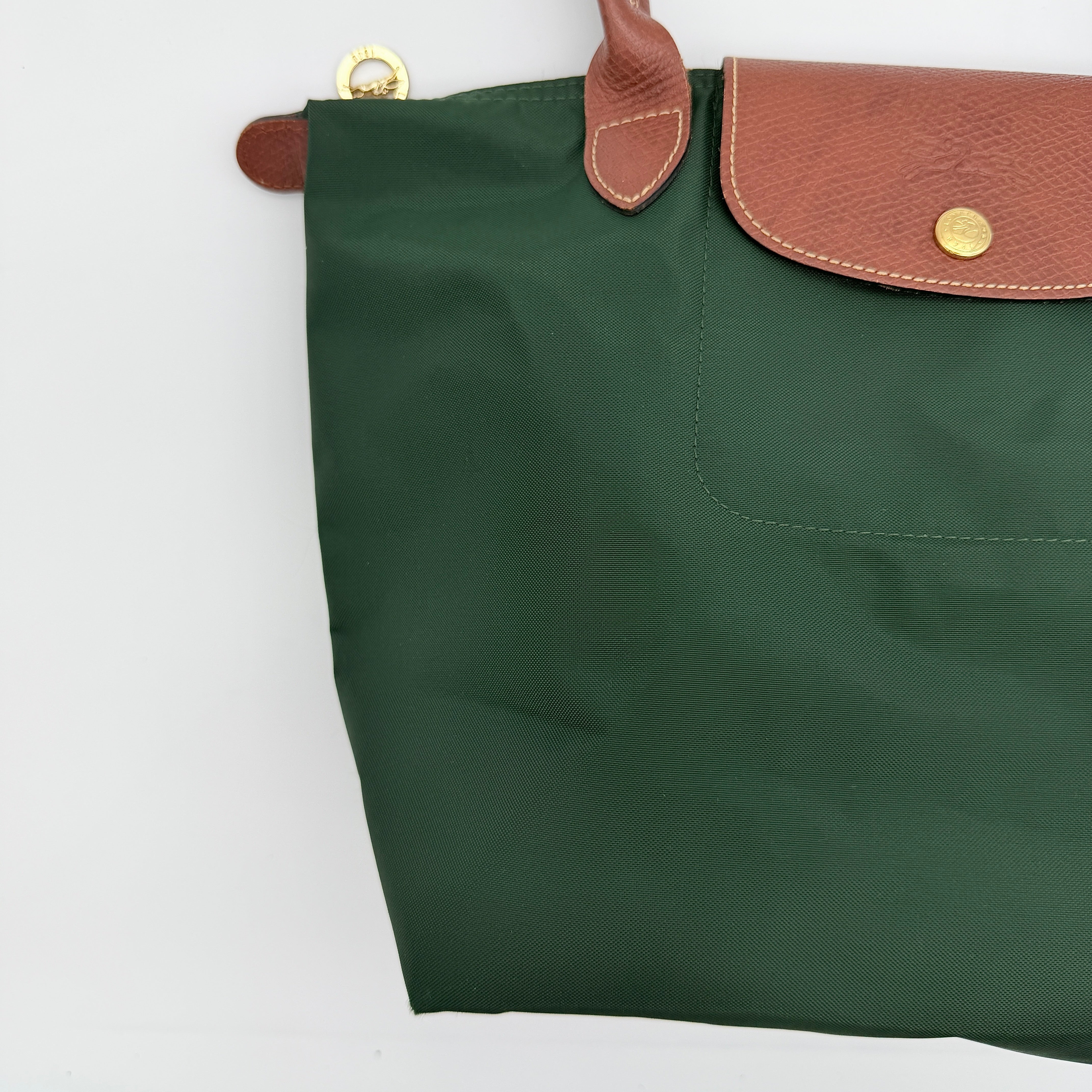 Longchamp Le Pliage Original Tote in green nylon with brown leather handles and gold hardware displayed against a white background.