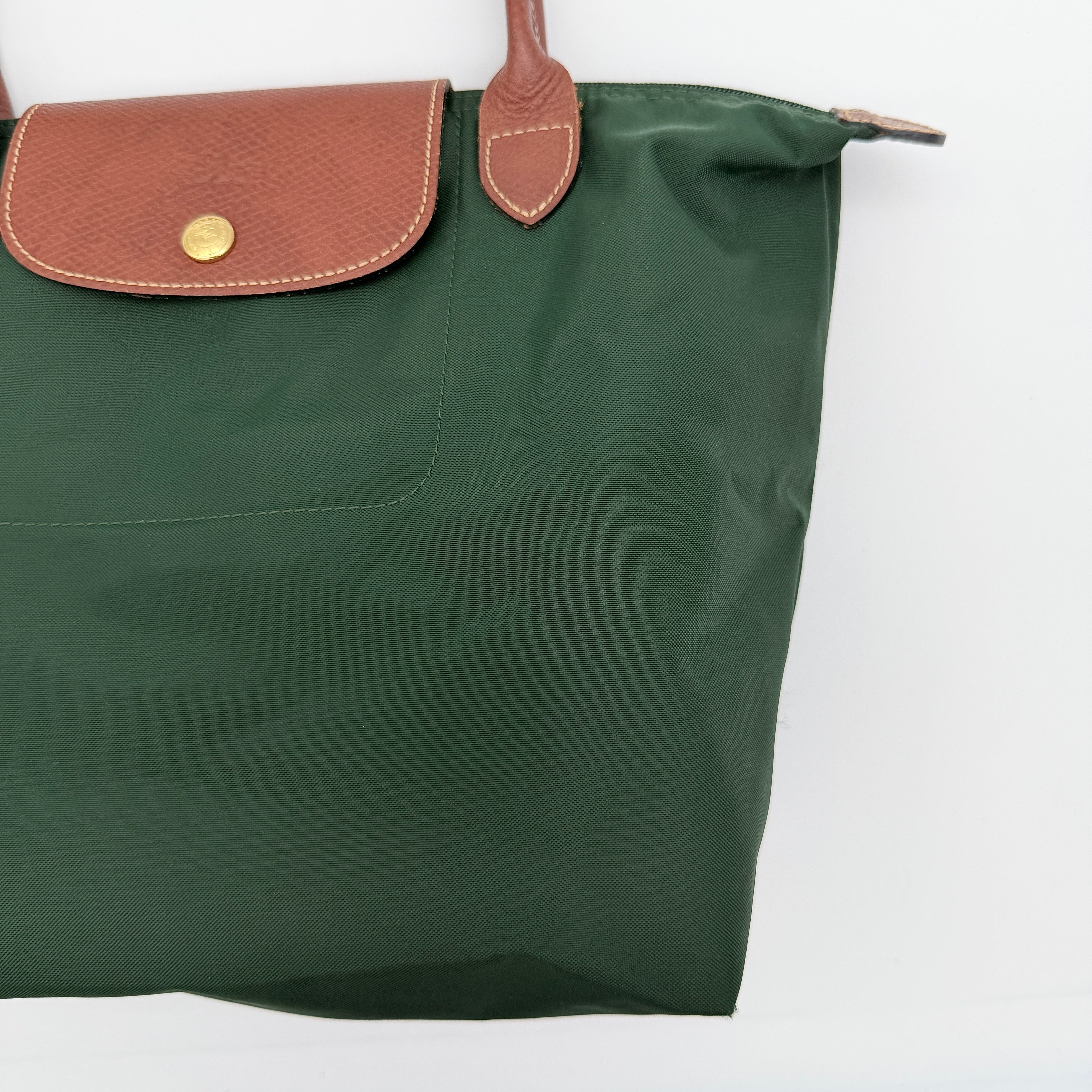 Longchamp Le Pliage Original Tote in green nylon with brown leather handles and gold hardware displayed against a white background.