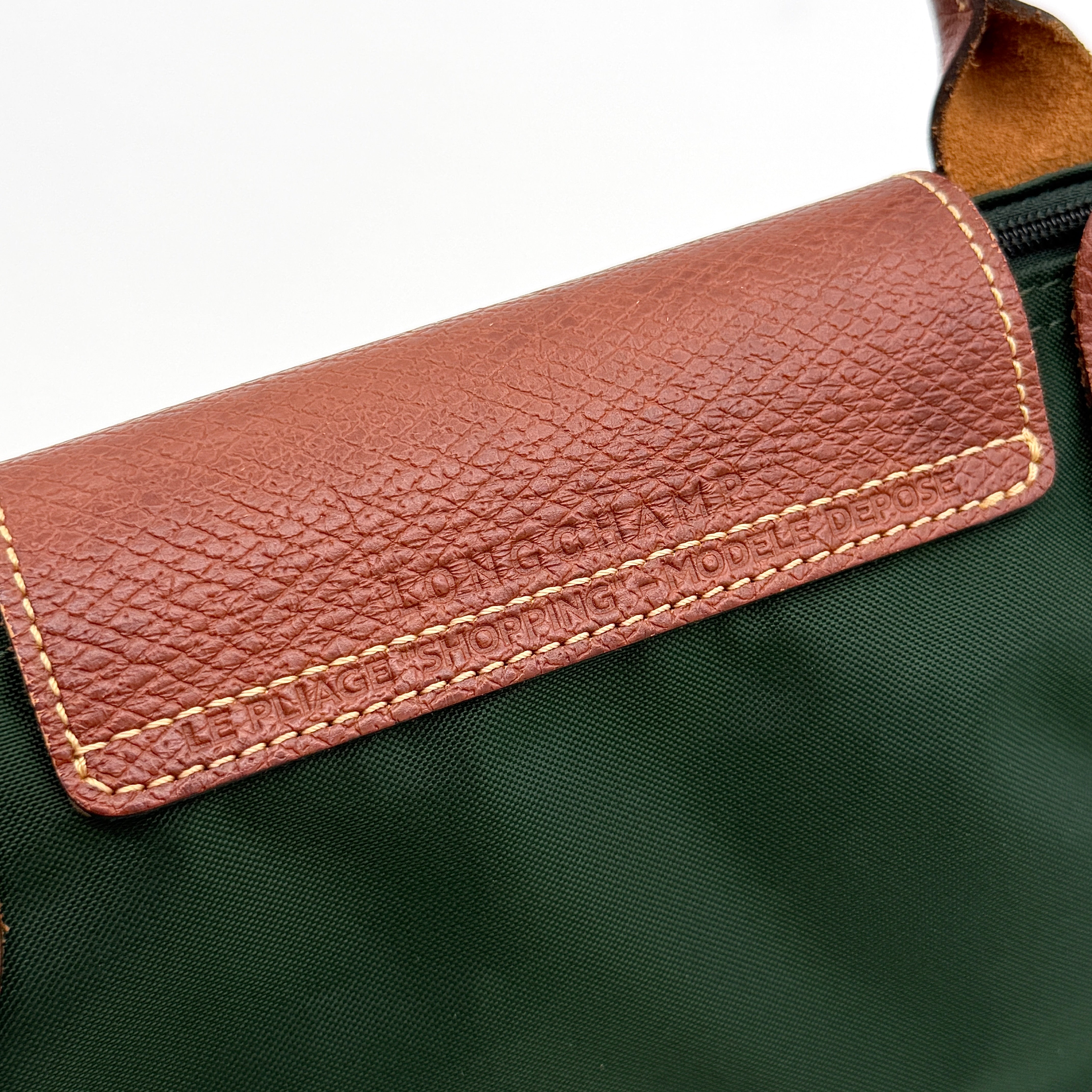 Longchamp Le Pliage Original Tote in green nylon with brown leather handles and gold hardware displayed against a white background.