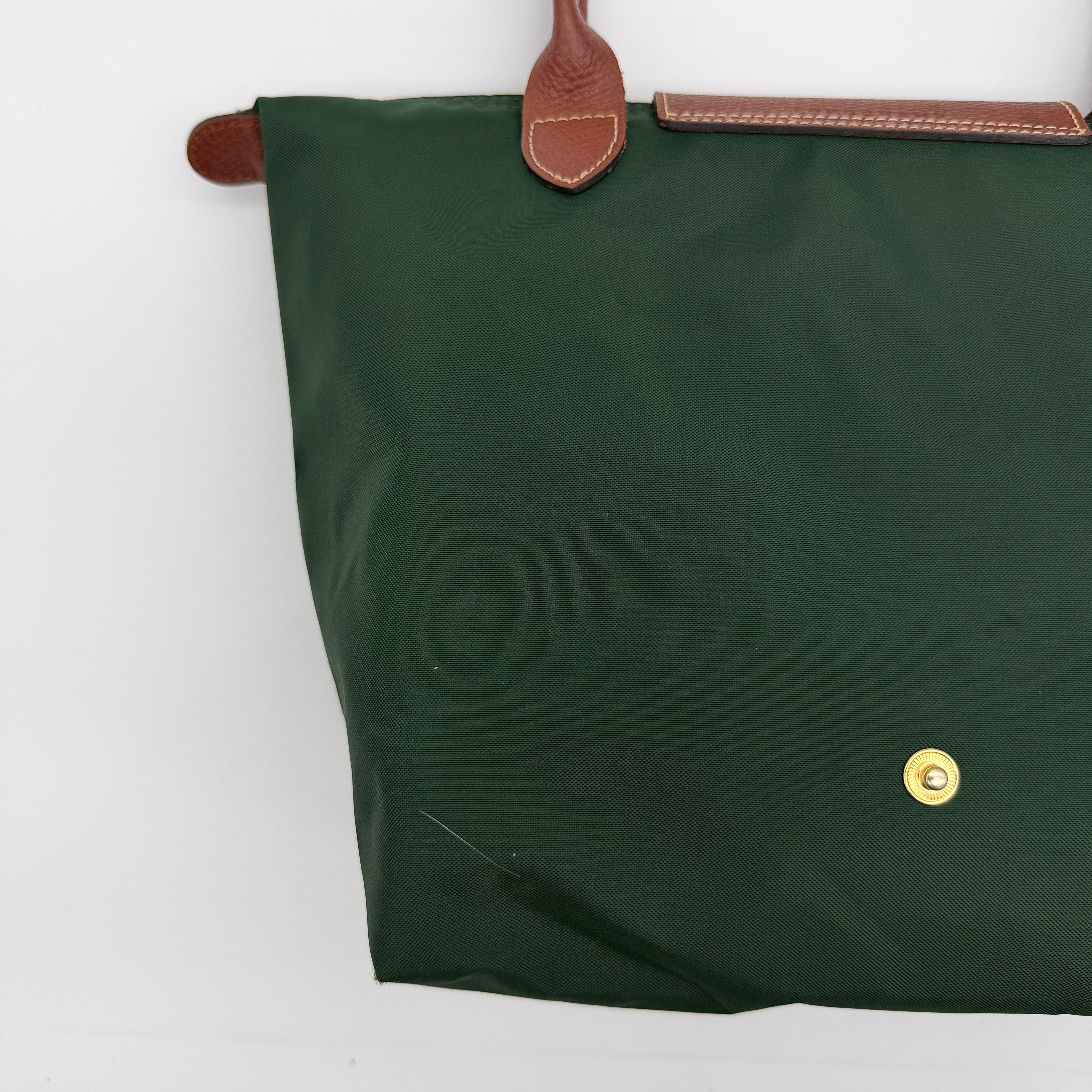 Longchamp Le Pliage Original Tote in green nylon with brown leather handles and gold hardware displayed against a white background.