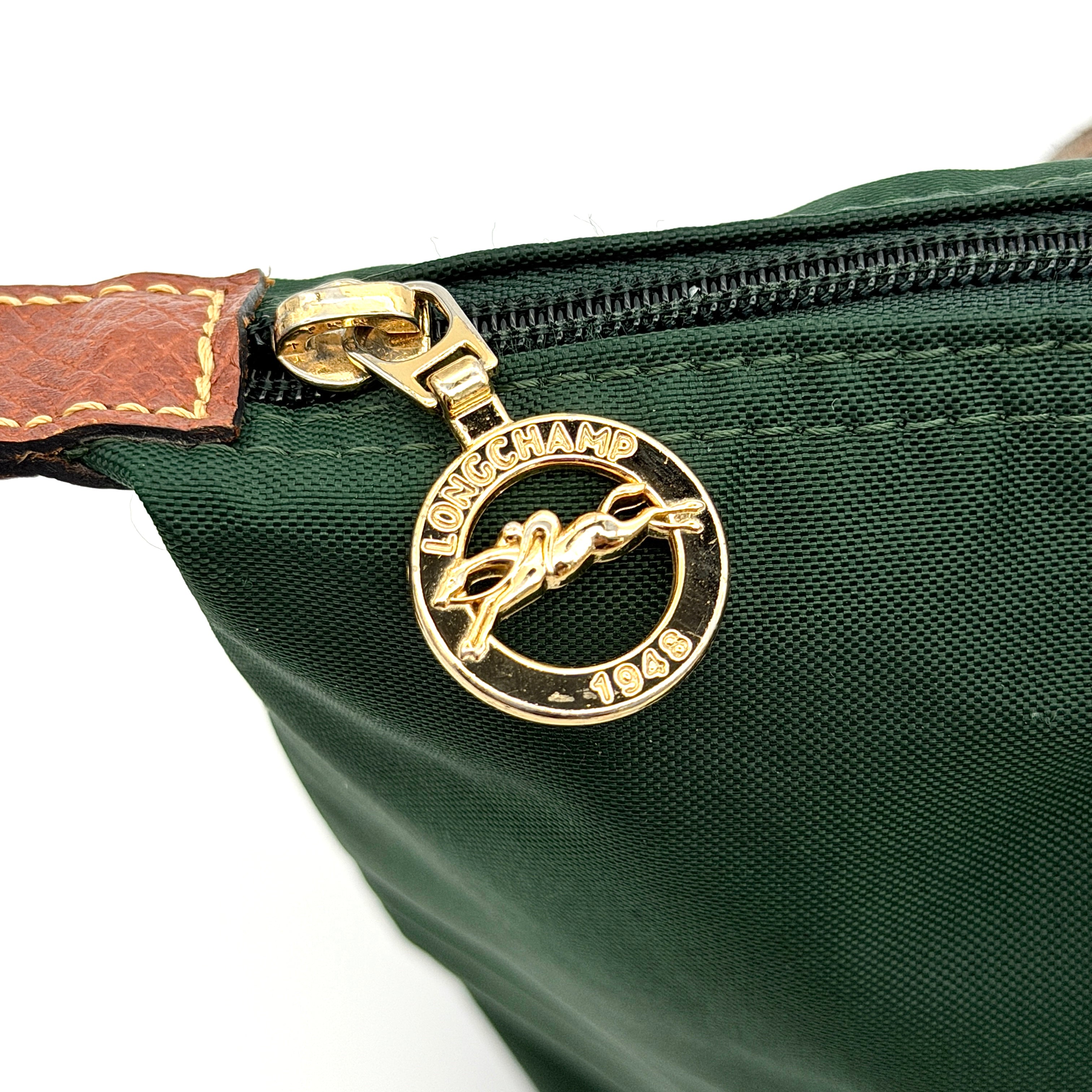 Longchamp Le Pliage Original Tote in green nylon with brown leather handles and gold hardware displayed against a white background.