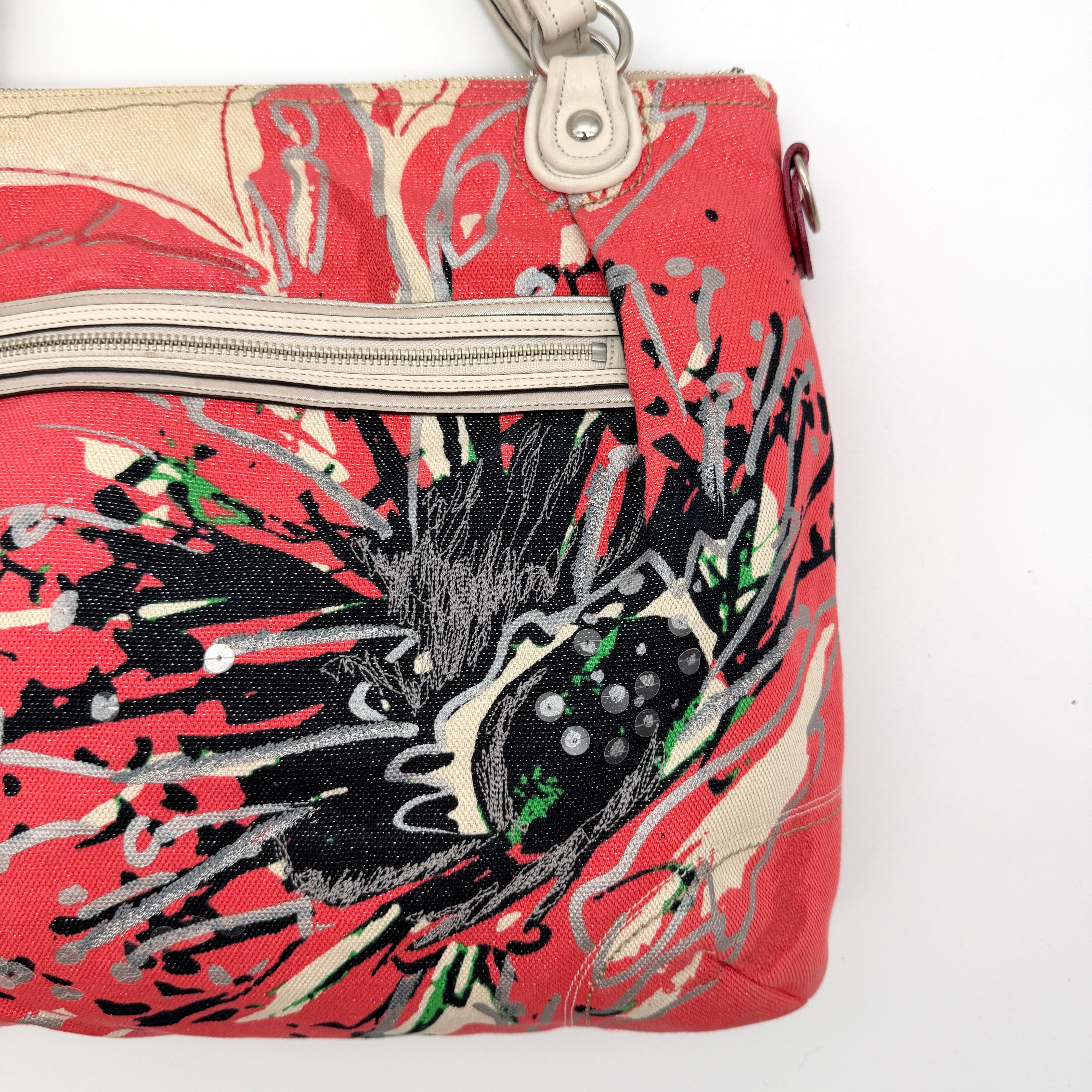 Coach Poppy Glam Floral Shoulder Bag in canvas with a bold multicolour floral print and cream leather handles, photographed on white.