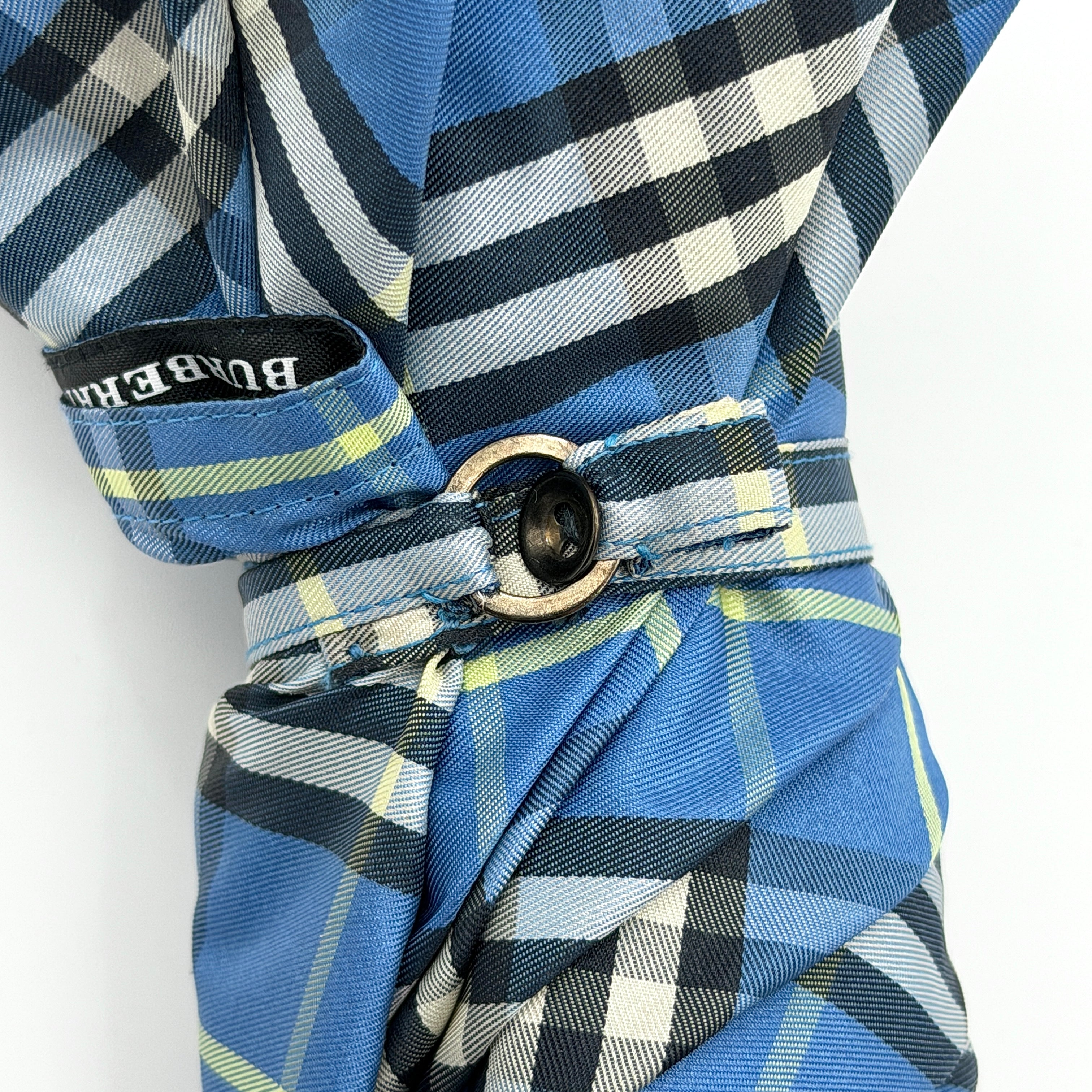 Burberry folding umbrella and matching pouch in blue Nova Check plaid, perfectly folded to showcase its classic pattern and refined finish.