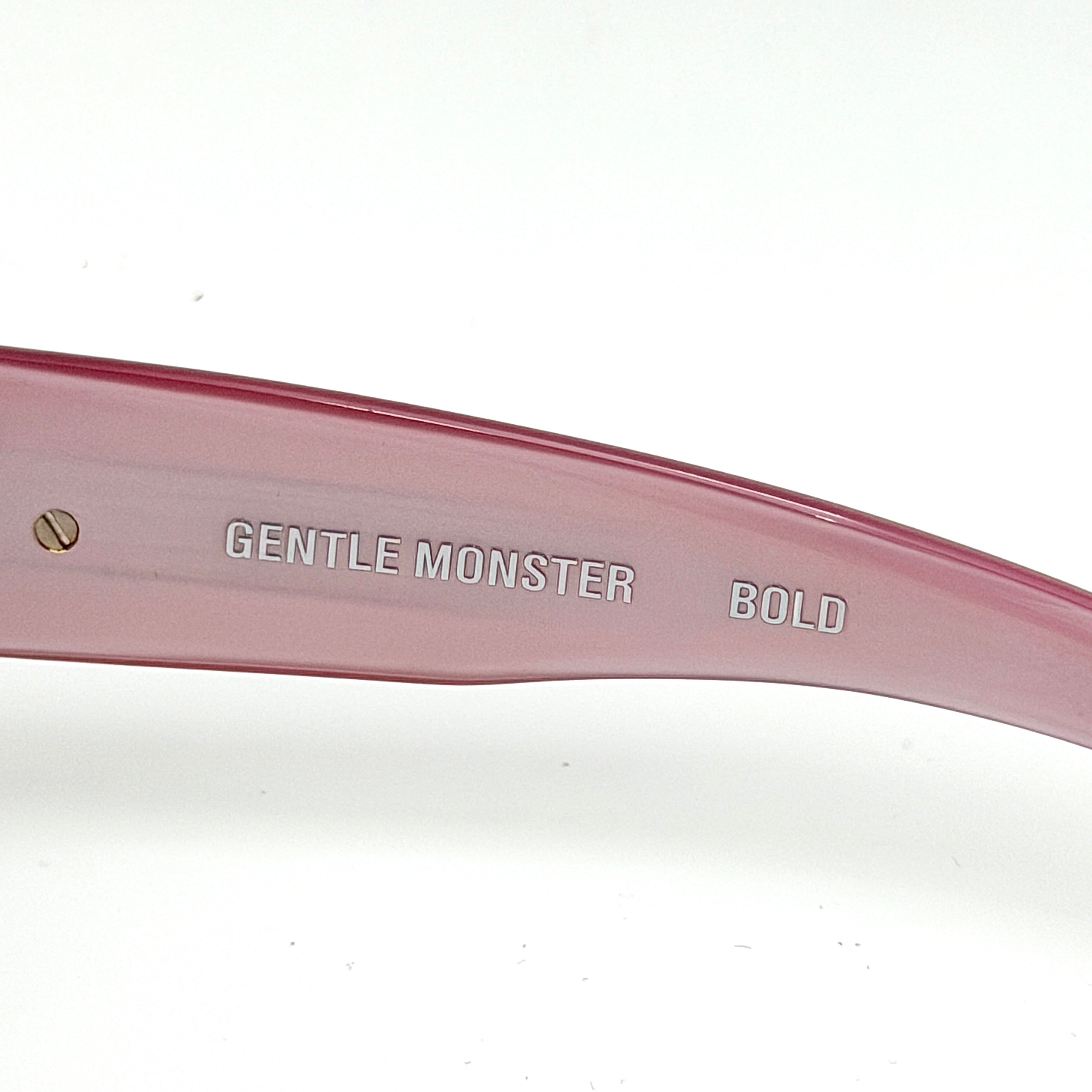 Gentle Monster R.E.A.T sunglasses in translucent pink acetate with mirrored pink lenses and silver star hardware, displayed alongside a chrome hard case.