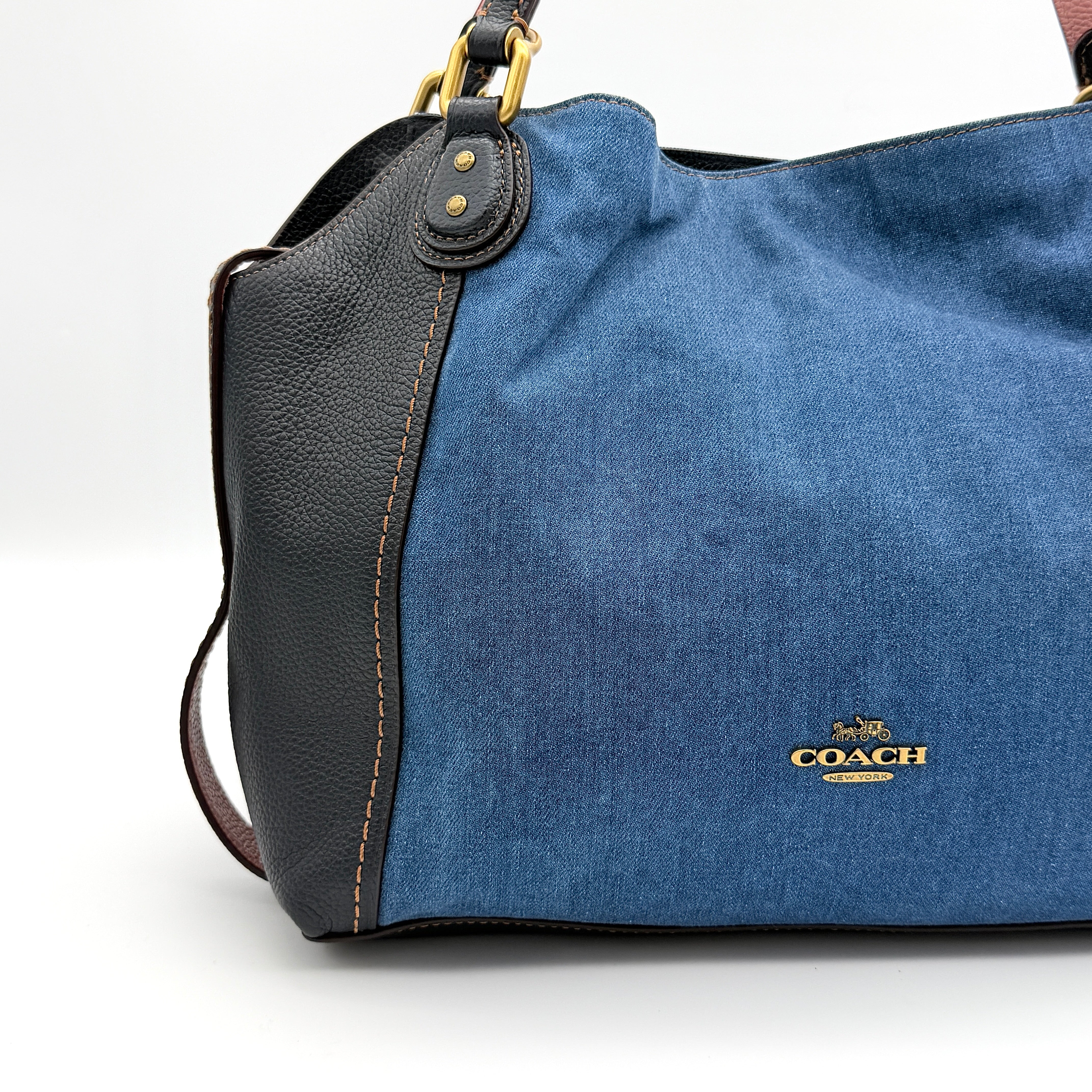 Coach Edie 2Way shoulder bag in navy denim with black leather trim, pink accents and gold hardware, shown with detachable strap.