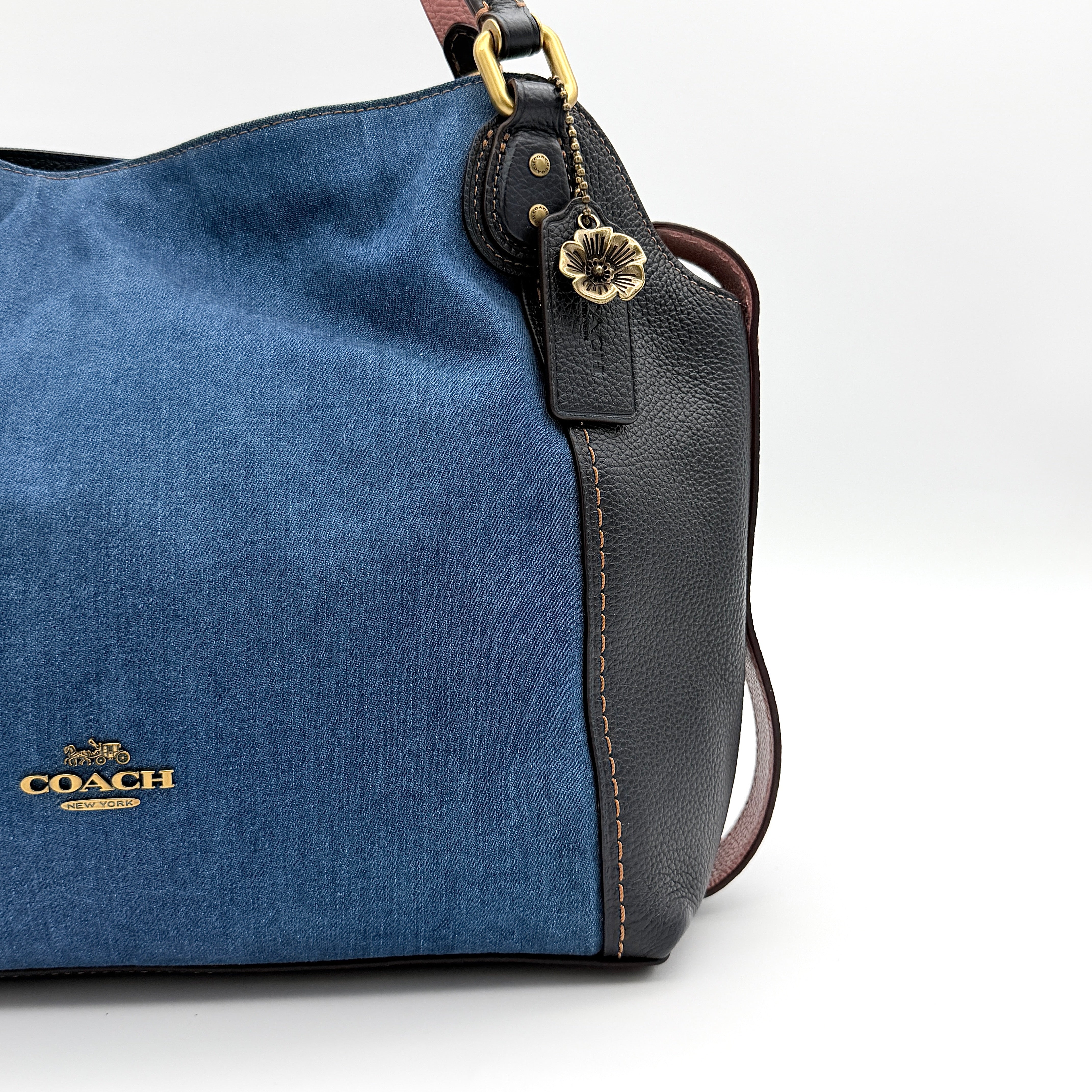 Coach Edie 2Way shoulder bag in navy denim with black leather trim, pink accents and gold hardware, shown with detachable strap.