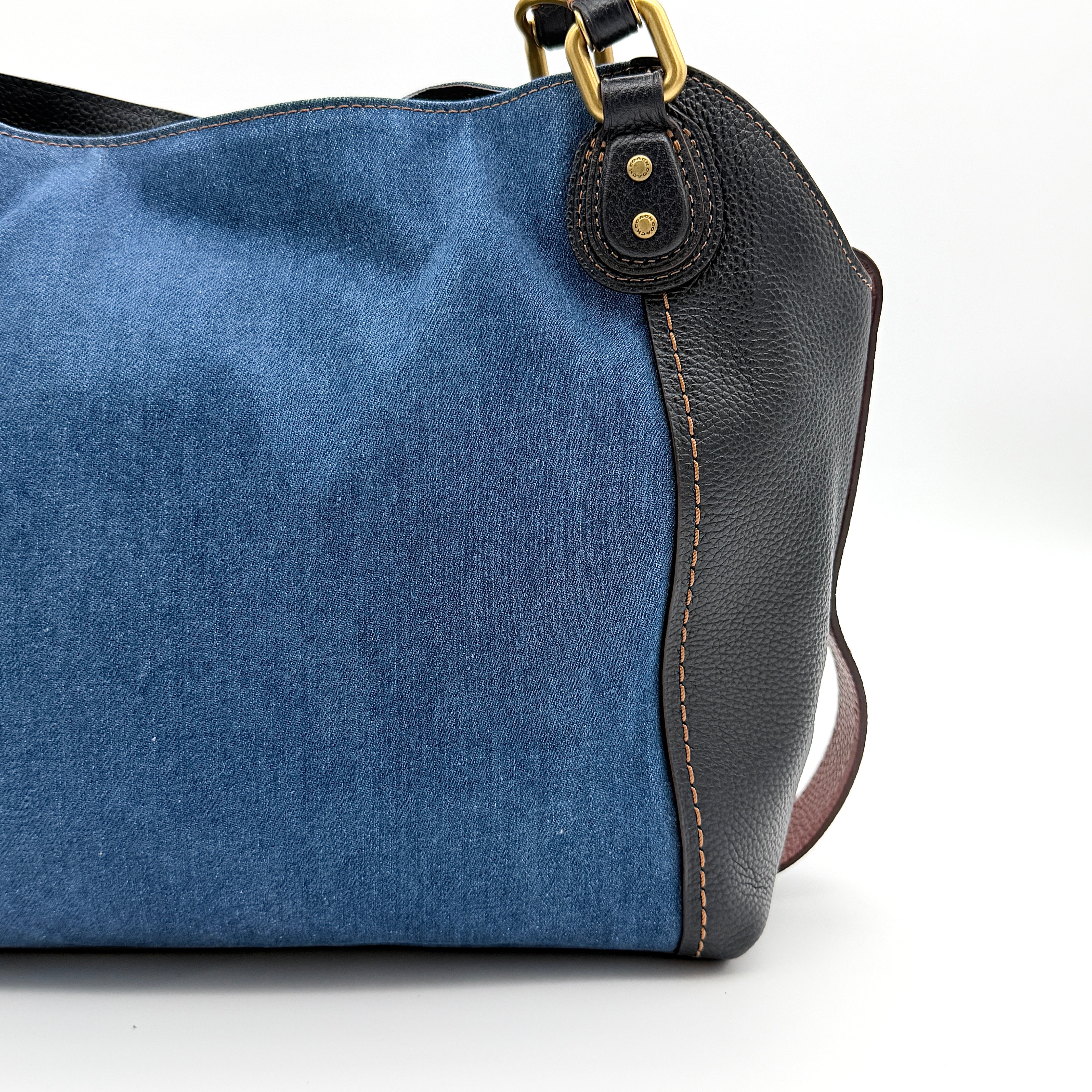 Coach Edie 2Way shoulder bag in navy denim with black leather trim, pink accents and gold hardware, shown with detachable strap.