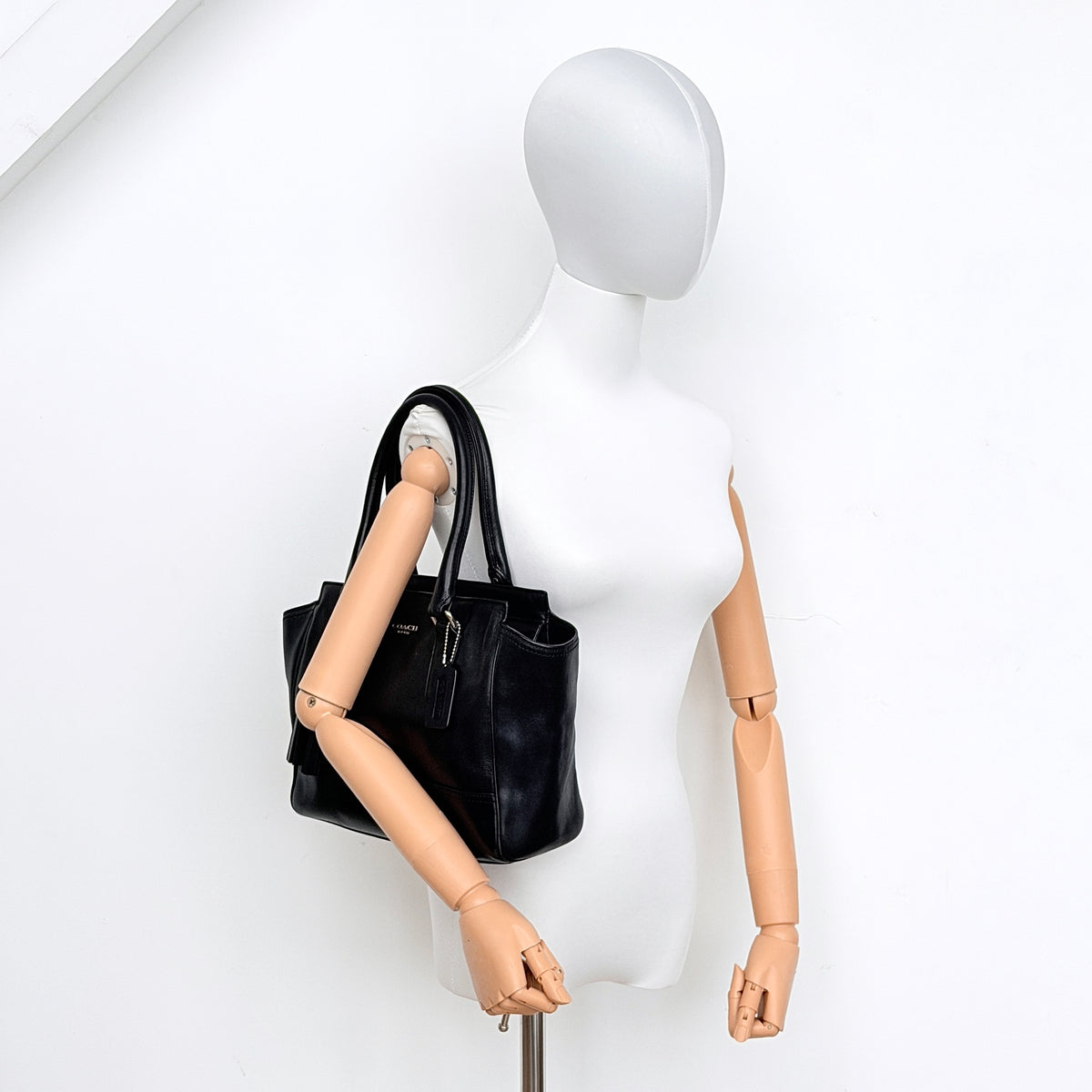 Coach Legacy Candace Carryall in black leather with double tassel charm and silver hardware, photographed against a white background.