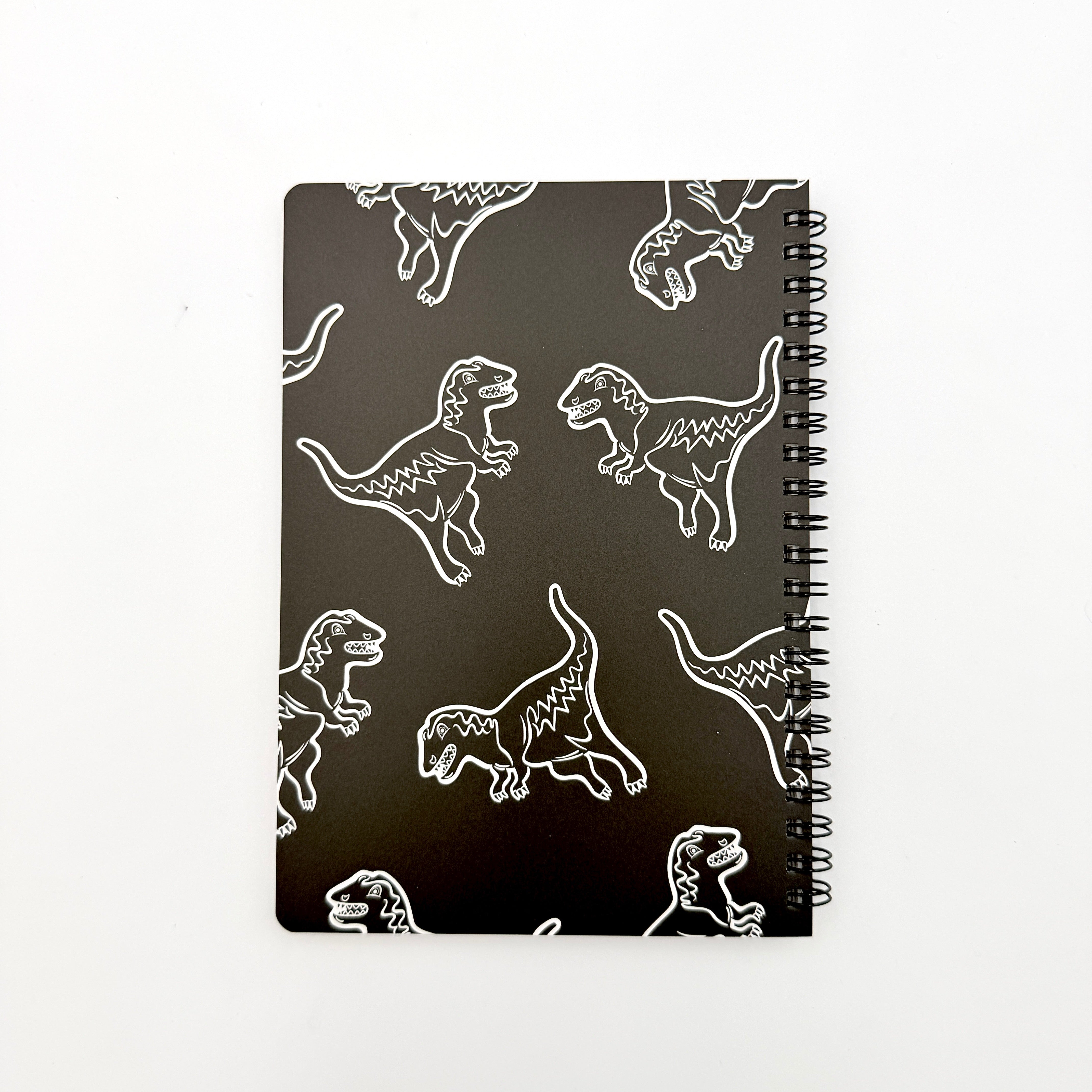 Coach Rexy Journal Notebook in black featuring white Rexy dinosaur illustrations and a spiral binding.