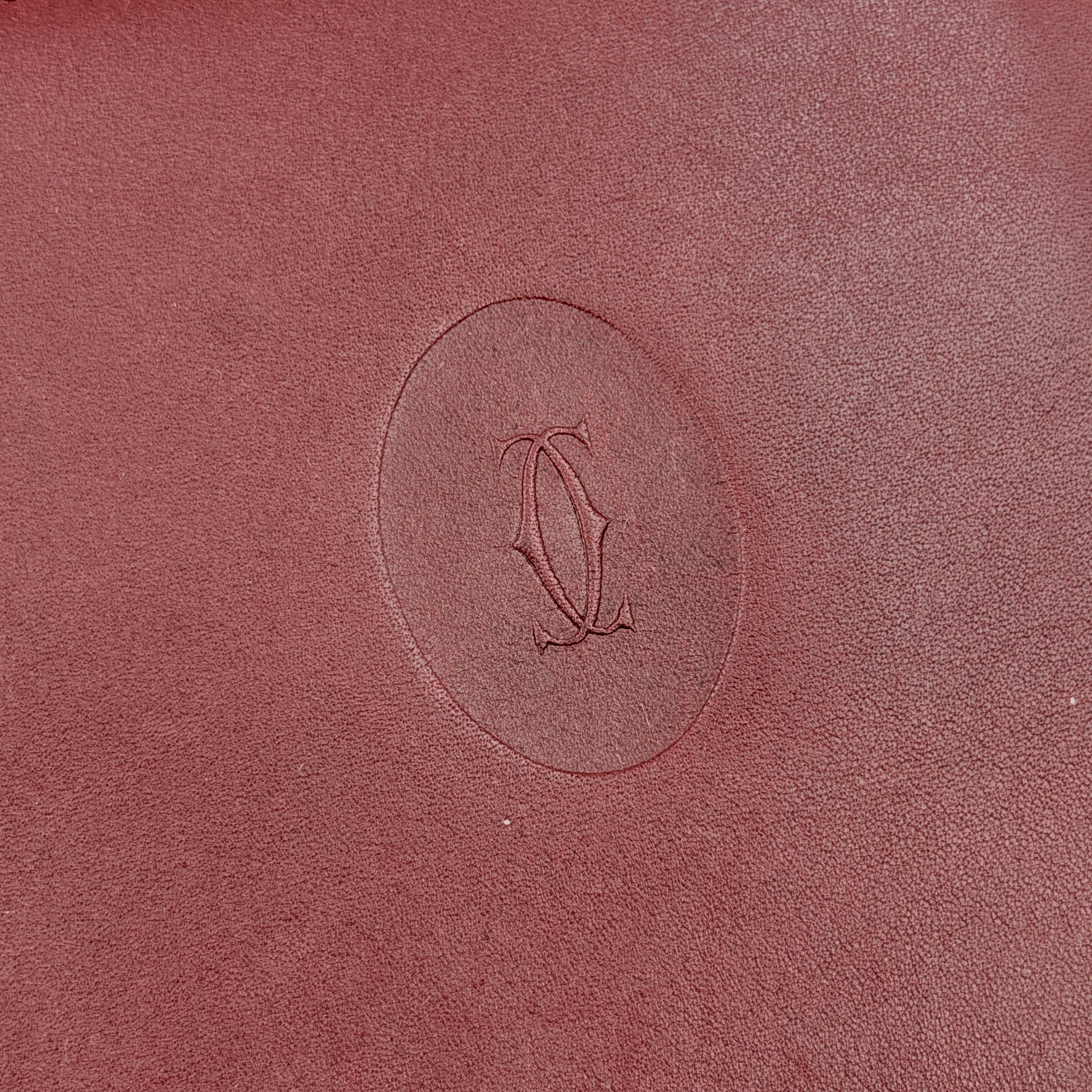 Cartier Must de Cartier leather wallet in rich burgundy with gold-tone corner accents and an embossed logo, photographed closed against a white background.