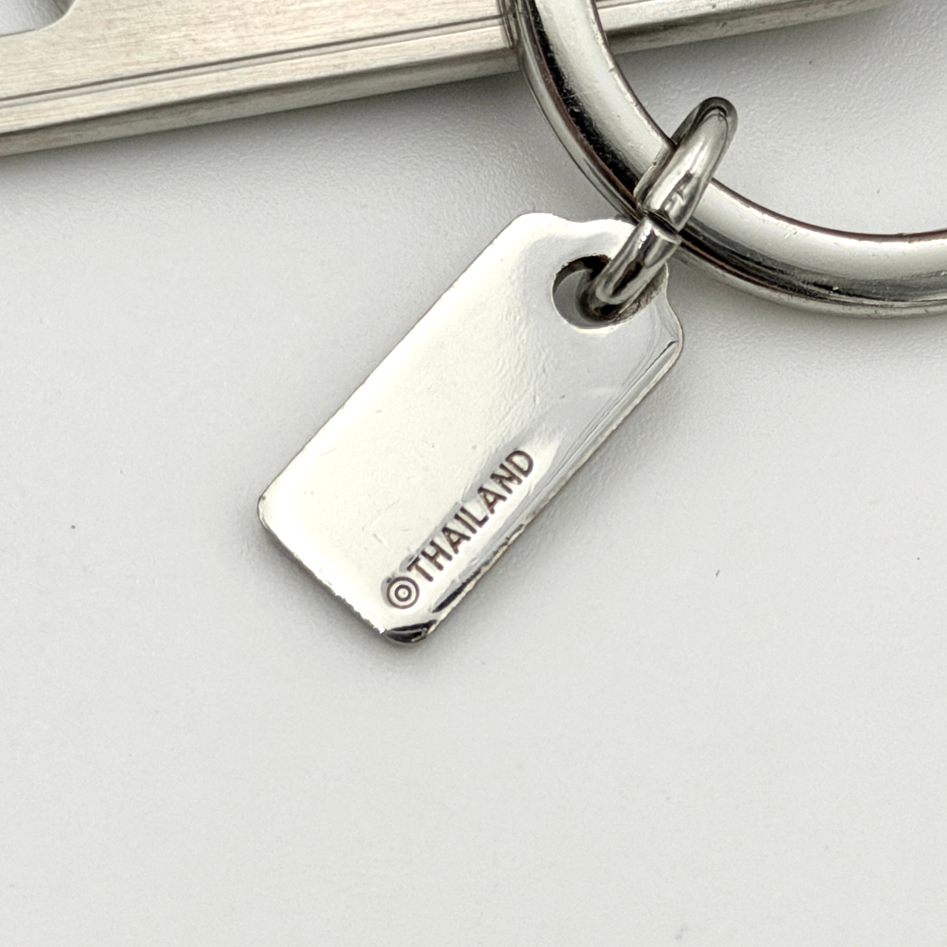 Coach bottle opener key fob in navy blue pebbled leather and silver-tone hardware, featuring a Coach New York embossed tag and integrated opener.