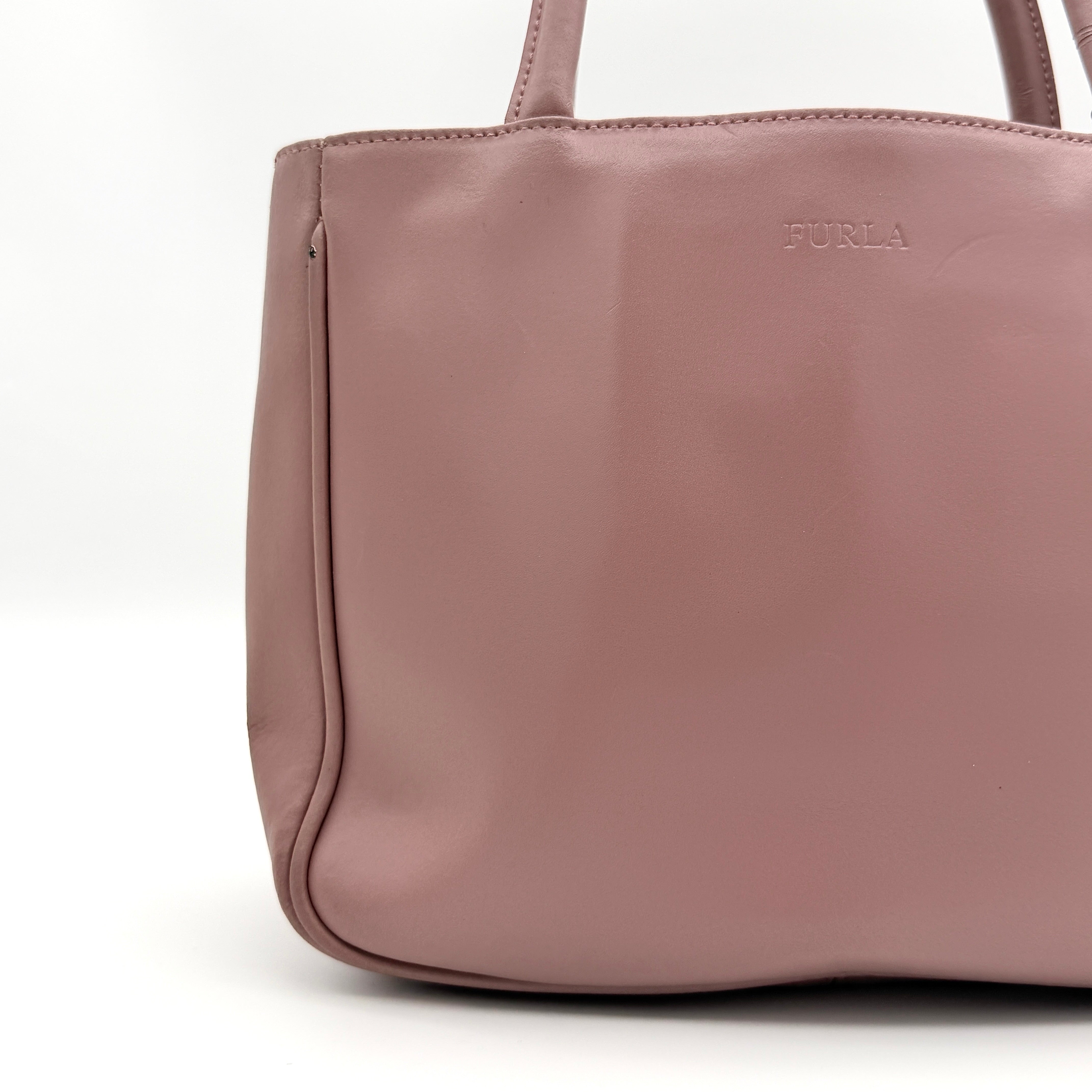 Furla 2Way Leather Handbag in pink with top handles, gold-tone charm, and a detachable strap, photographed on a white background.