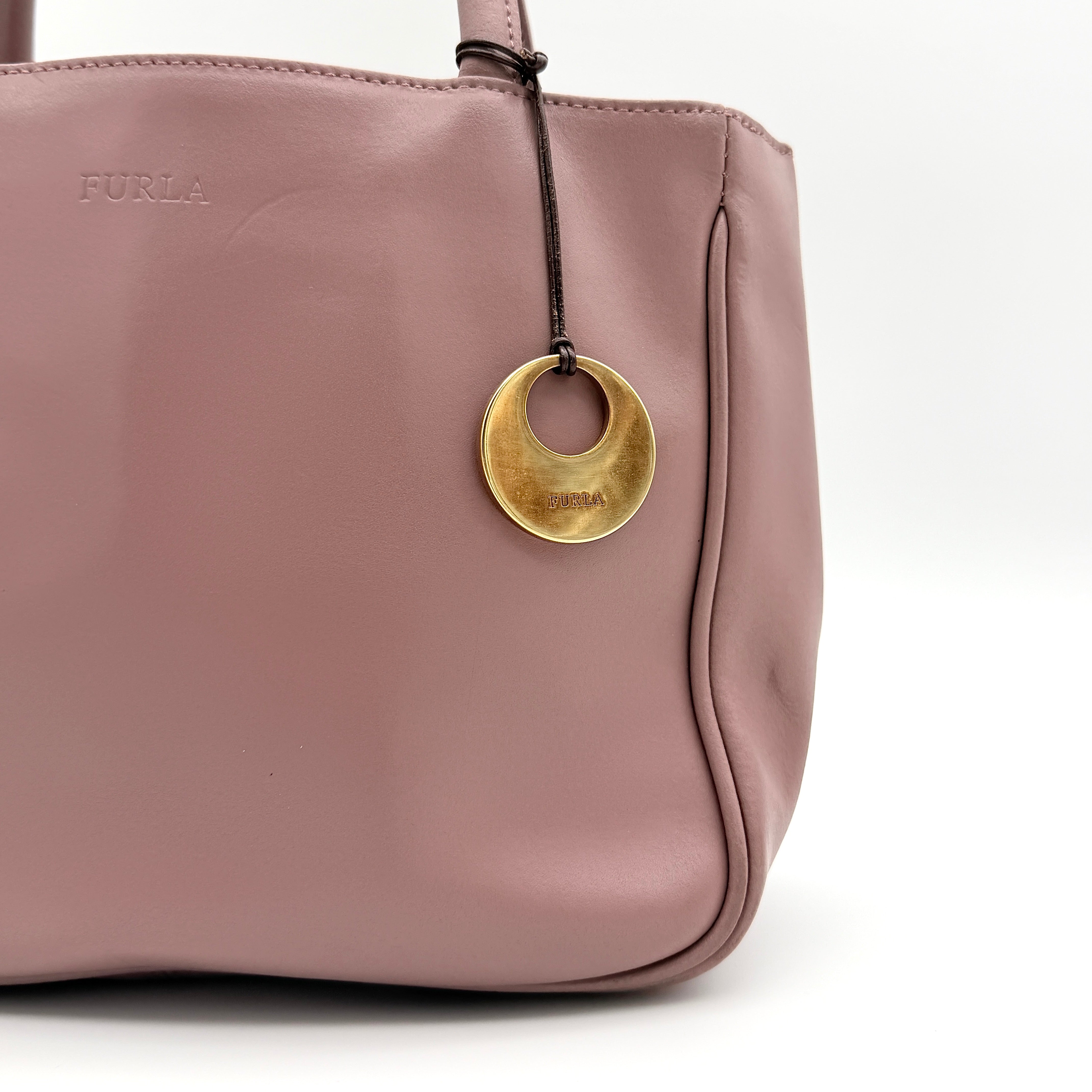 Furla 2Way Leather Handbag in pink with top handles, gold-tone charm, and a detachable strap, photographed on a white background.
