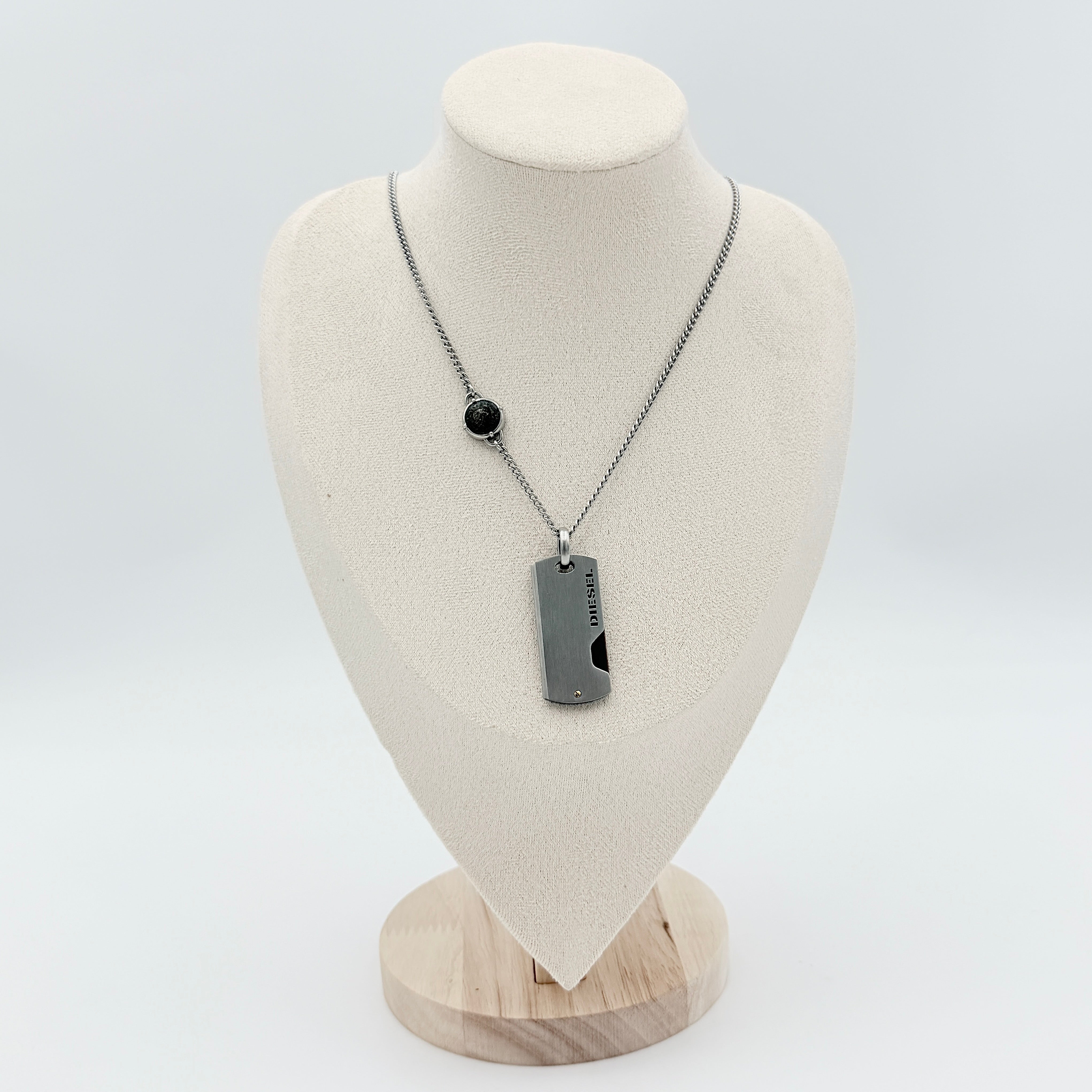 Diesel silver-tone stainless steel dog tag necklace with bronze accent, curb chain, and round detail showcased on a white background.