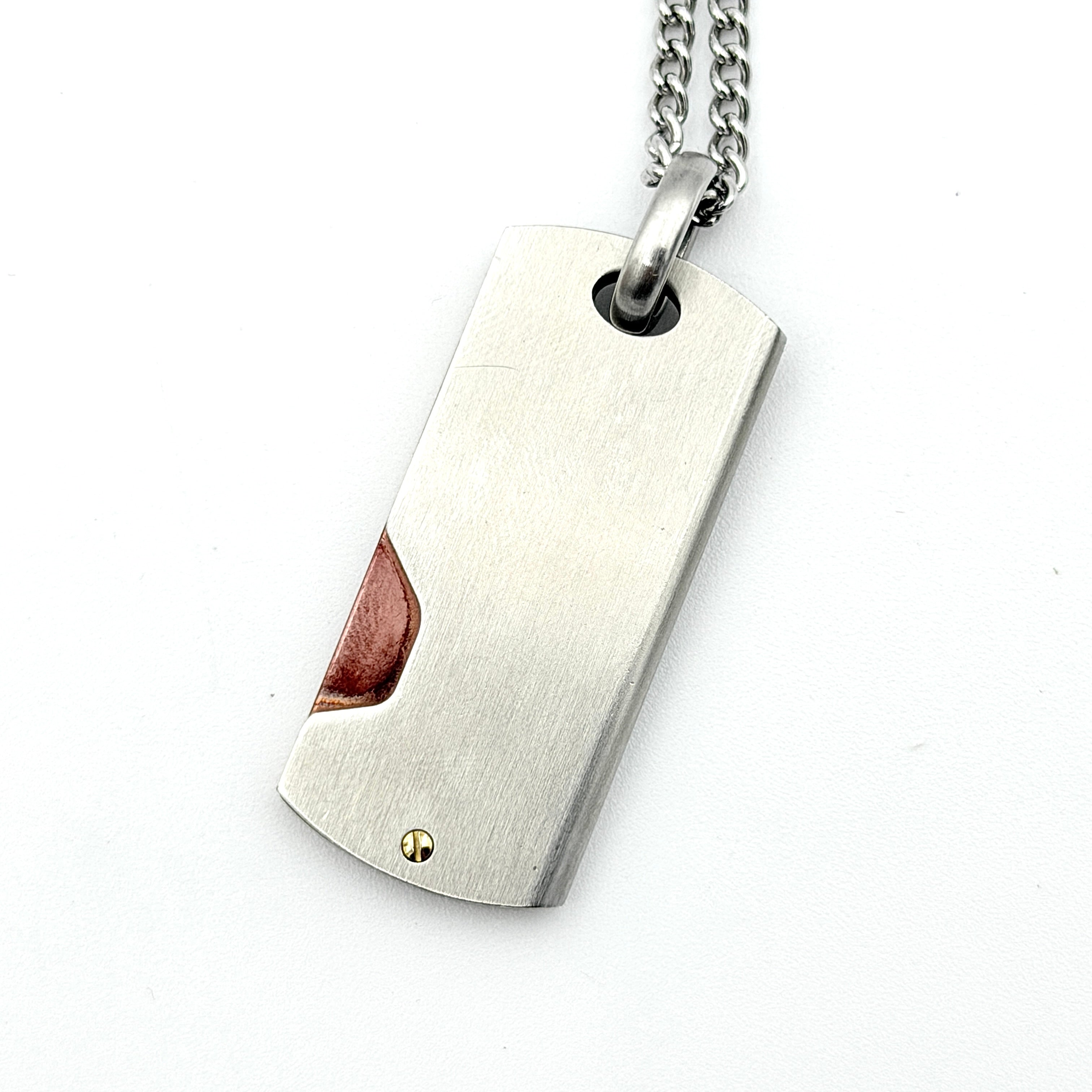 Diesel silver-tone stainless steel dog tag necklace with bronze accent, curb chain, and round detail showcased on a white background.