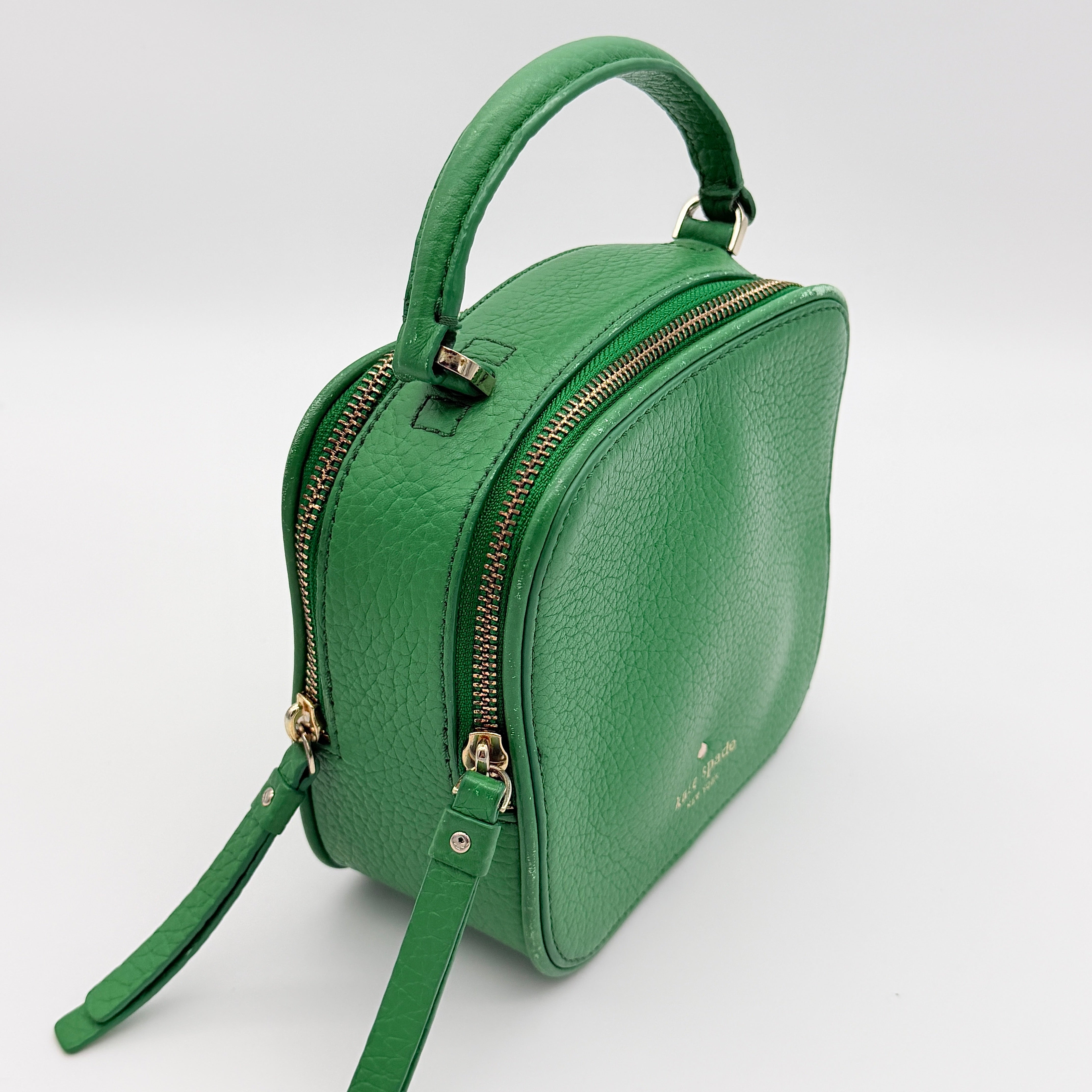 Kate Spade 2Way Vanity Crossbody Bag in bright green pebbled leather with top handle and detachable strap displayed in studio lighting.