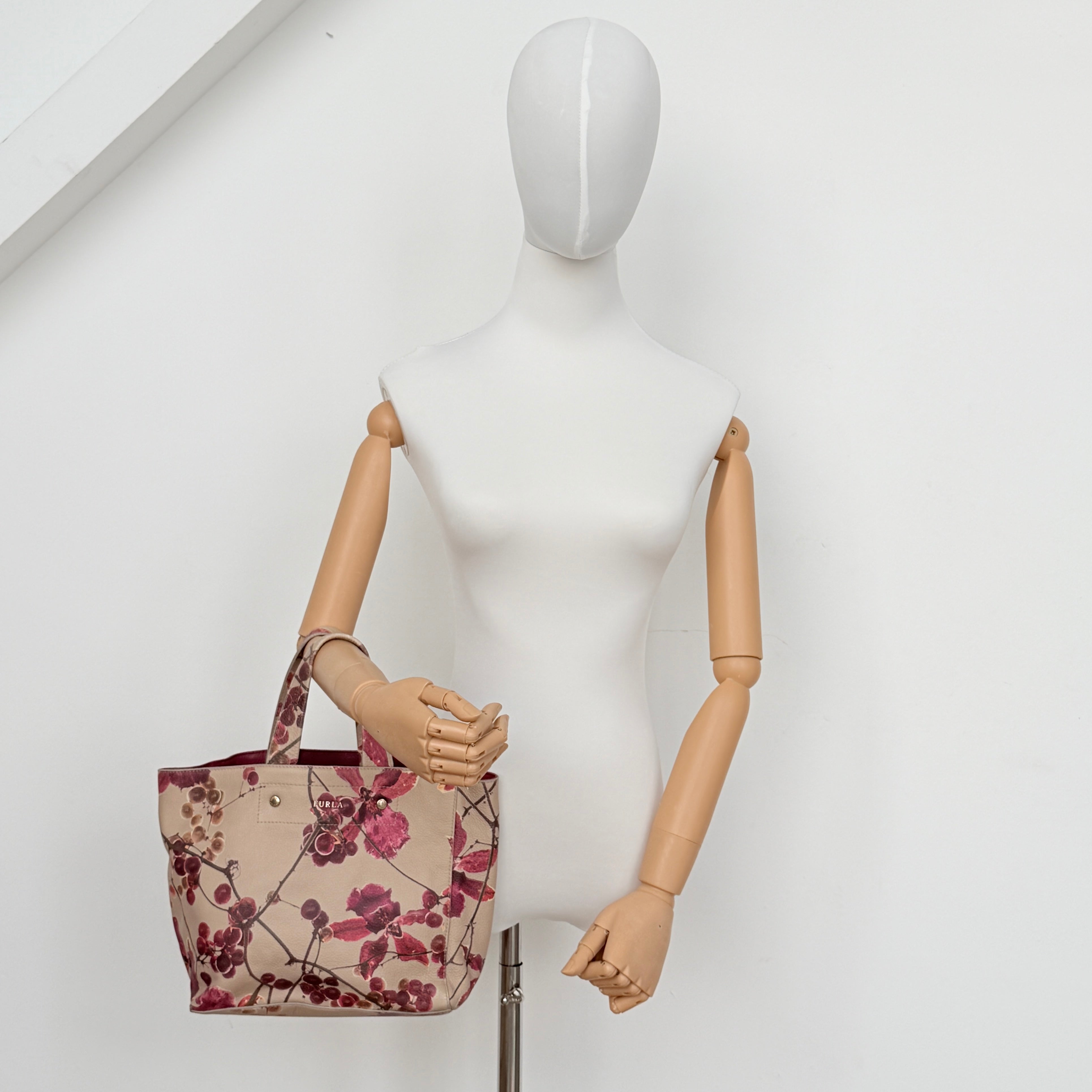 Furla beige leather tote bag adorned with a bold magenta and plum floral print, featuring structured short handles.