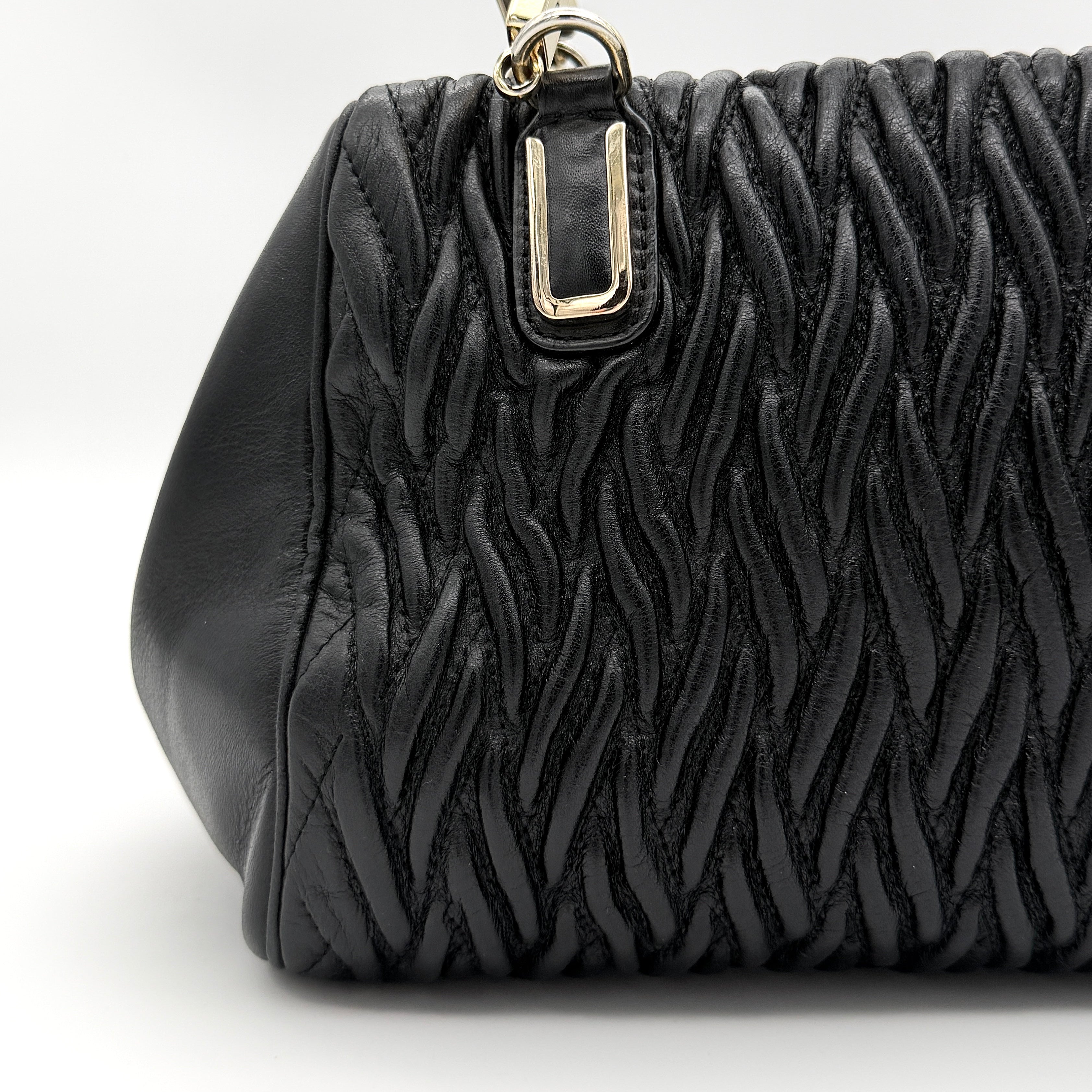 Coach Madison Gathered Twist satchel in black leather with gold hardware and detachable strap, styled on a white background.