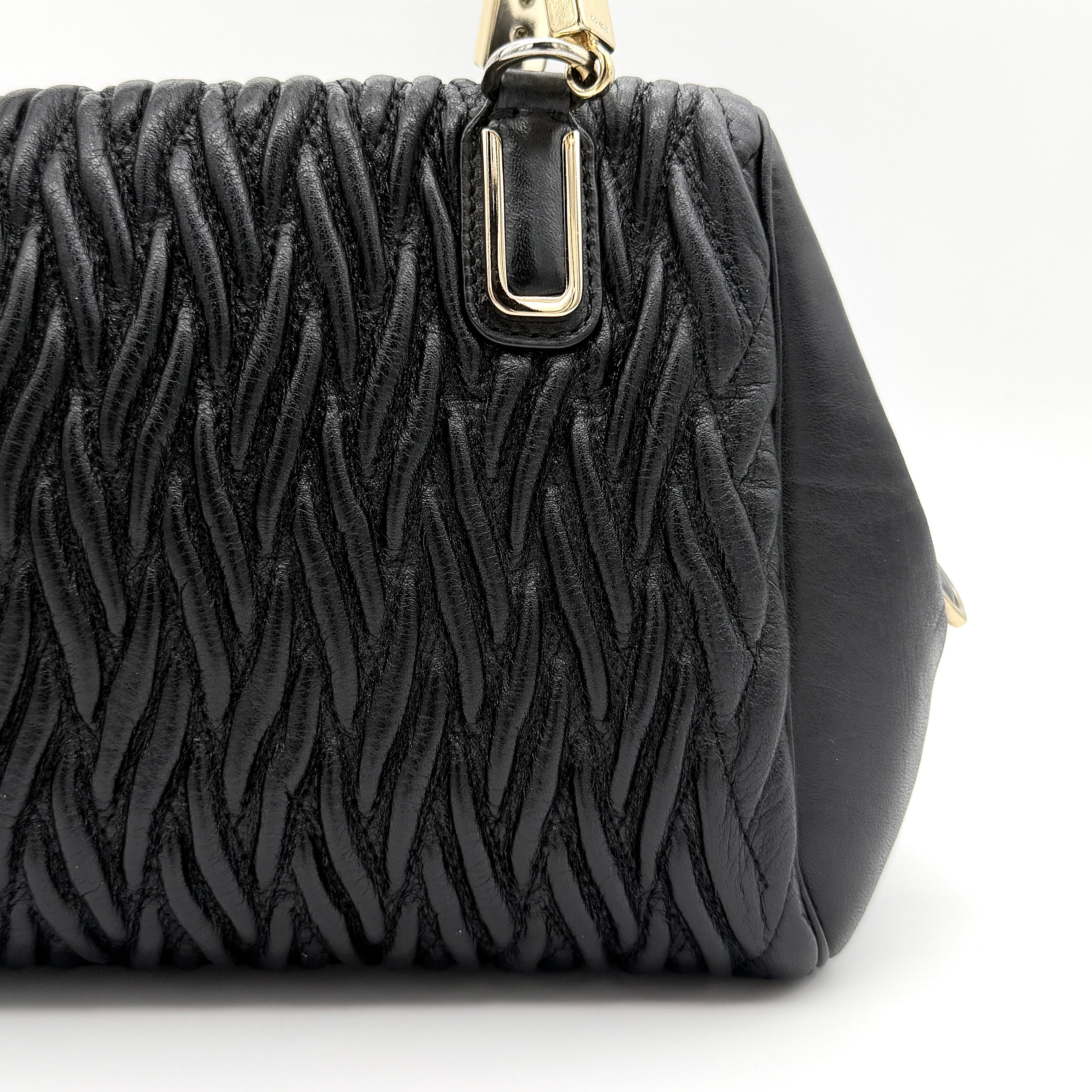 Coach Madison Gathered Twist satchel in black leather with gold hardware and detachable strap, styled on a white background.
