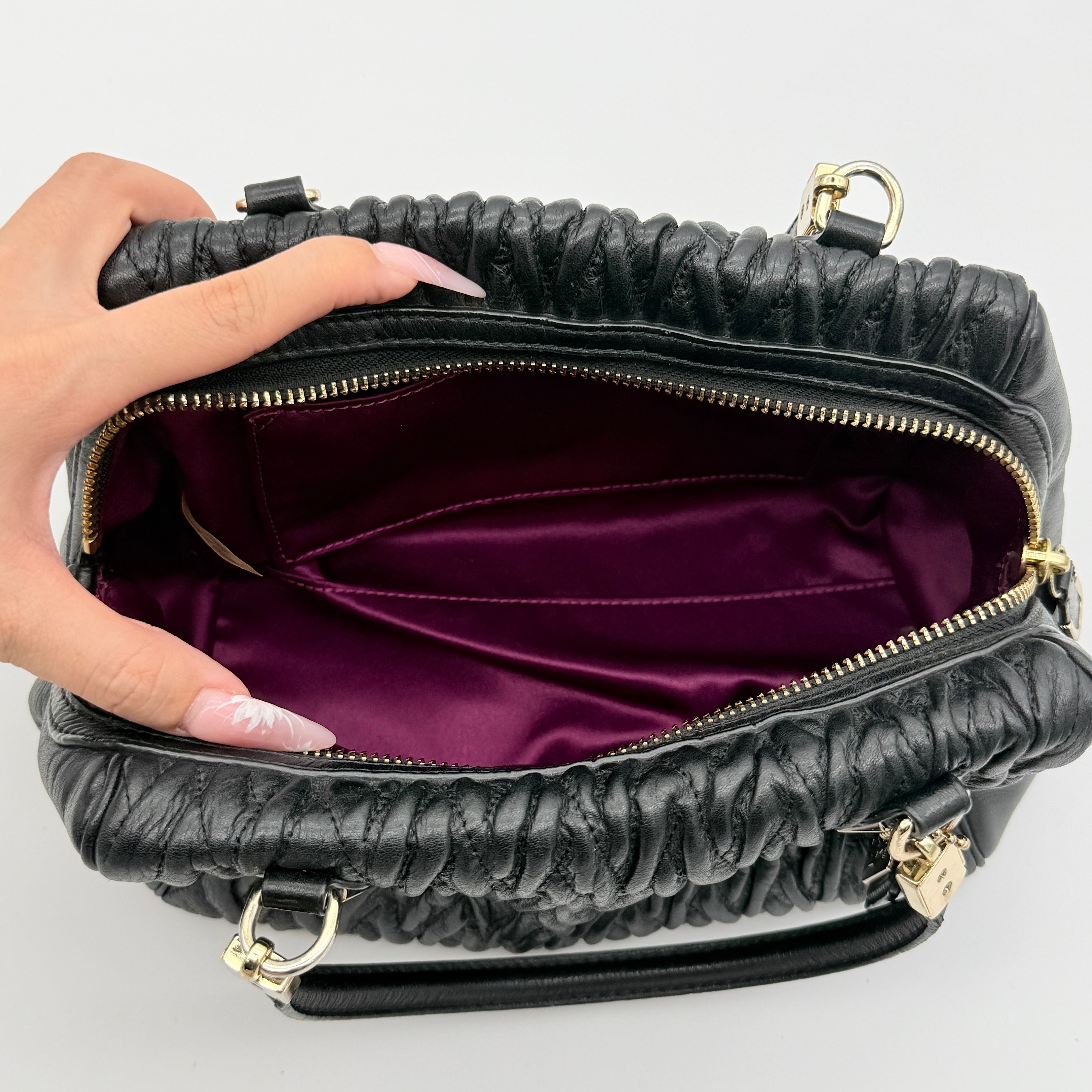 Coach Madison Gathered Twist satchel in black leather with gold hardware and detachable strap, styled on a white background.
