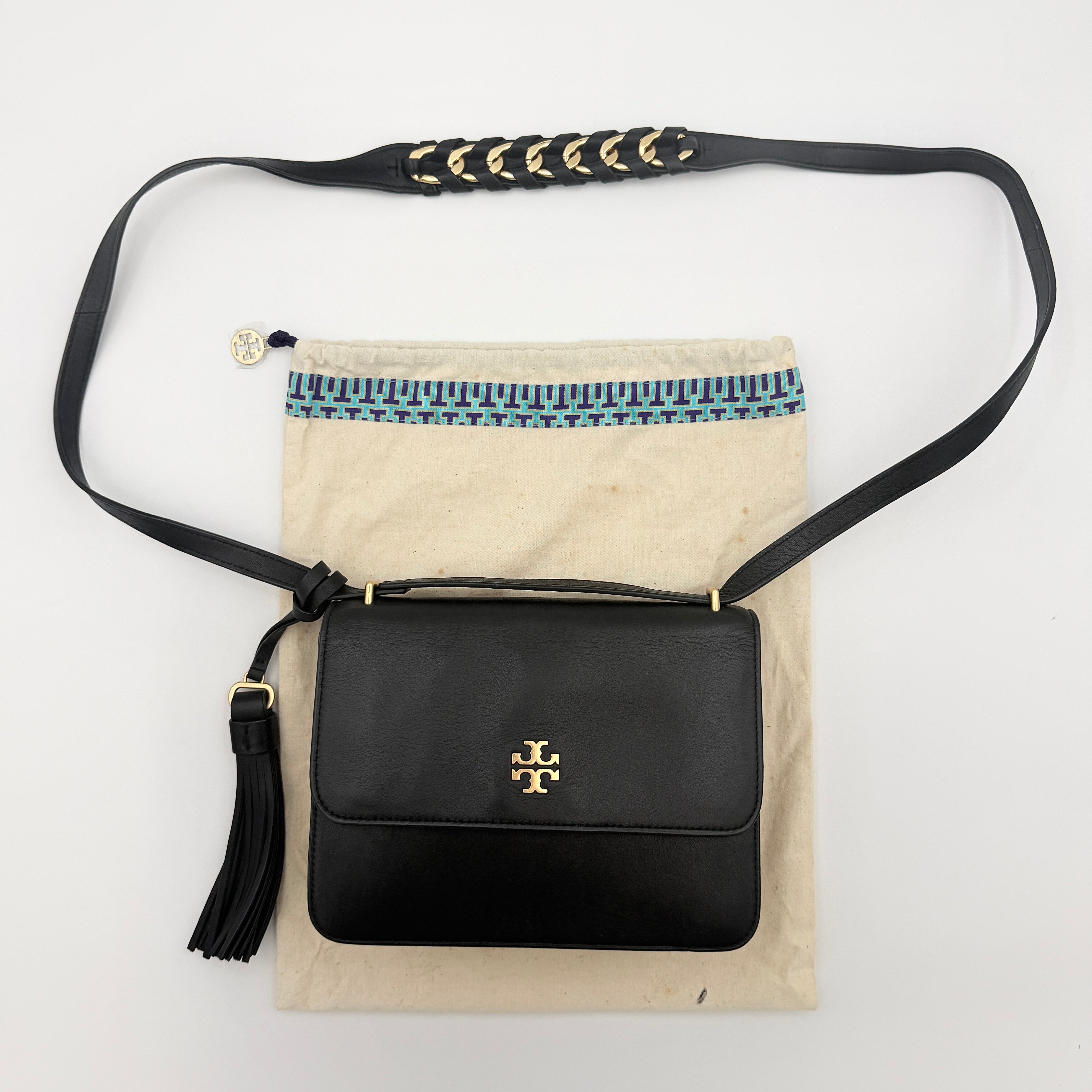 Tory Burch Brooke Crossbody Bag in black leather with gold-tone logo and a braided chain strap, elegantly displayed against a white backdrop.