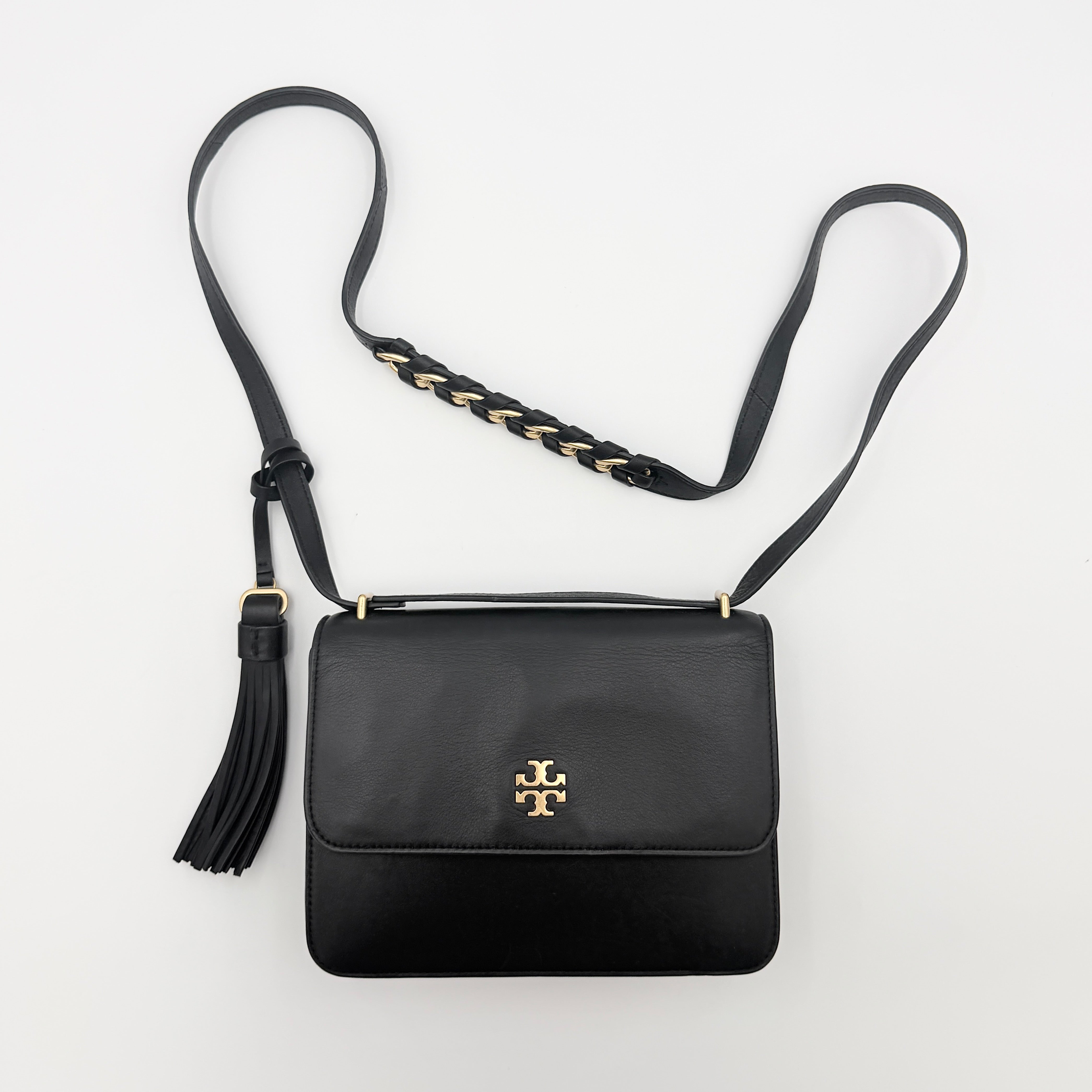 Tory Burch Brooke Crossbody Bag in black leather with gold-tone logo and a braided chain strap, elegantly displayed against a white backdrop.
