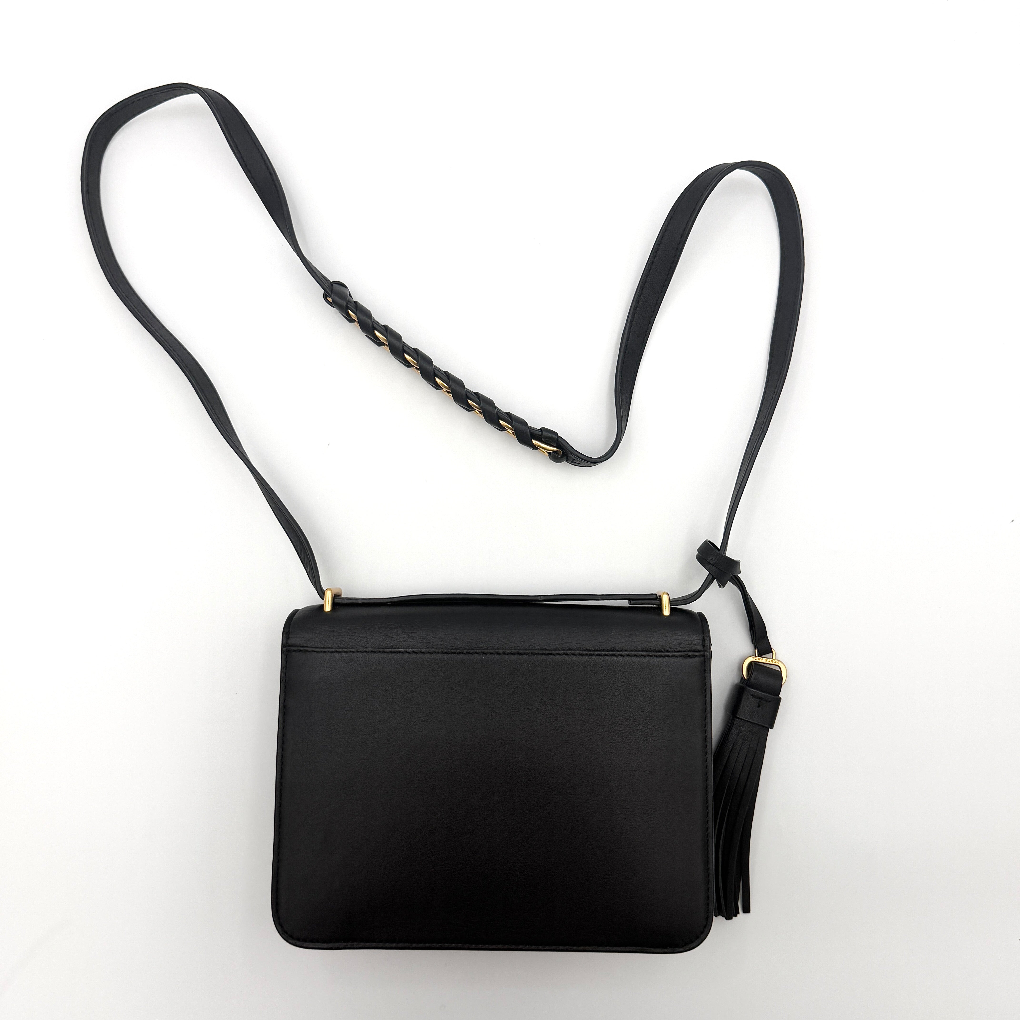 Tory Burch Brooke Crossbody Bag in black leather with gold-tone logo and a braided chain strap, elegantly displayed against a white backdrop.