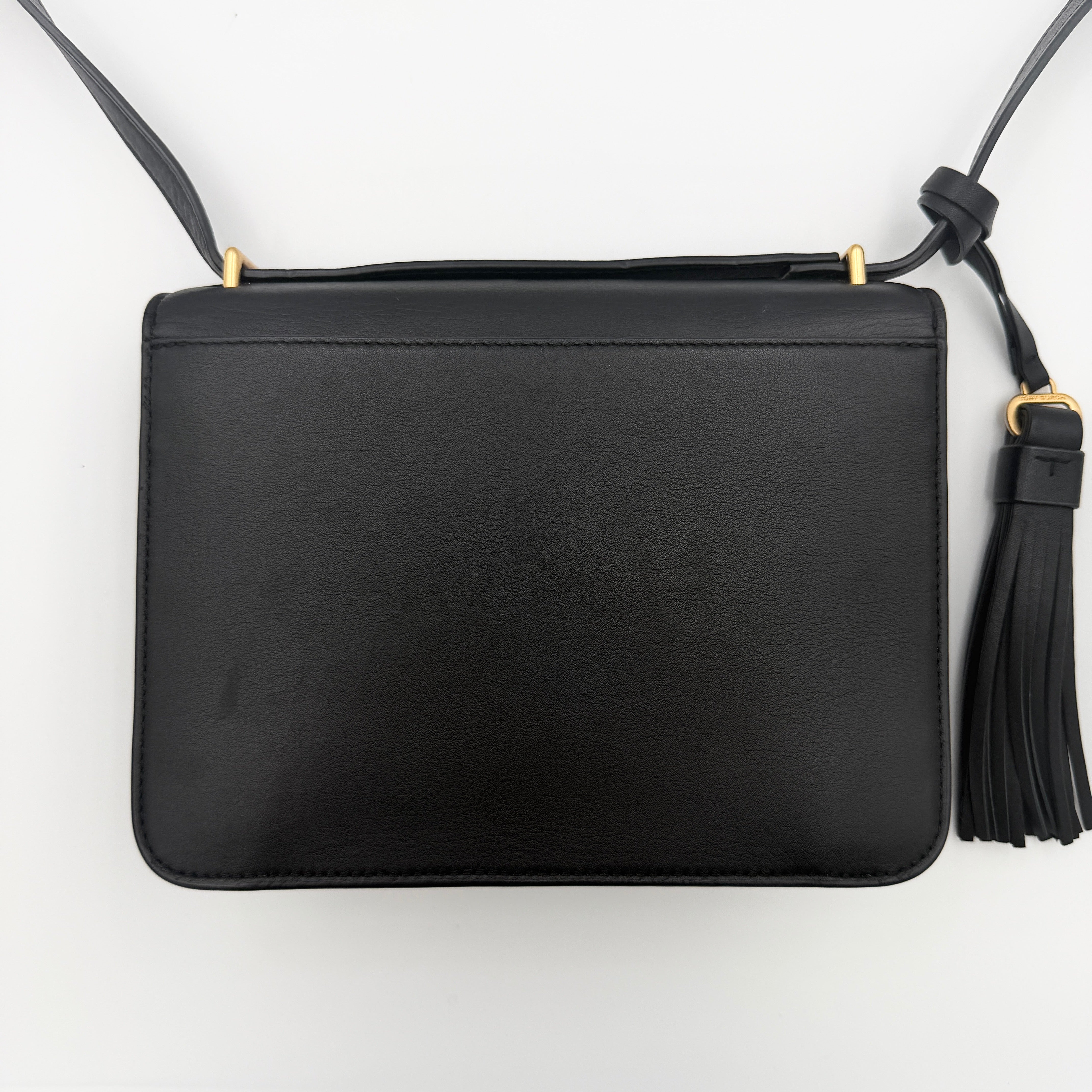 Tory Burch Brooke Crossbody Bag in black leather with gold-tone logo and a braided chain strap, elegantly displayed against a white backdrop.