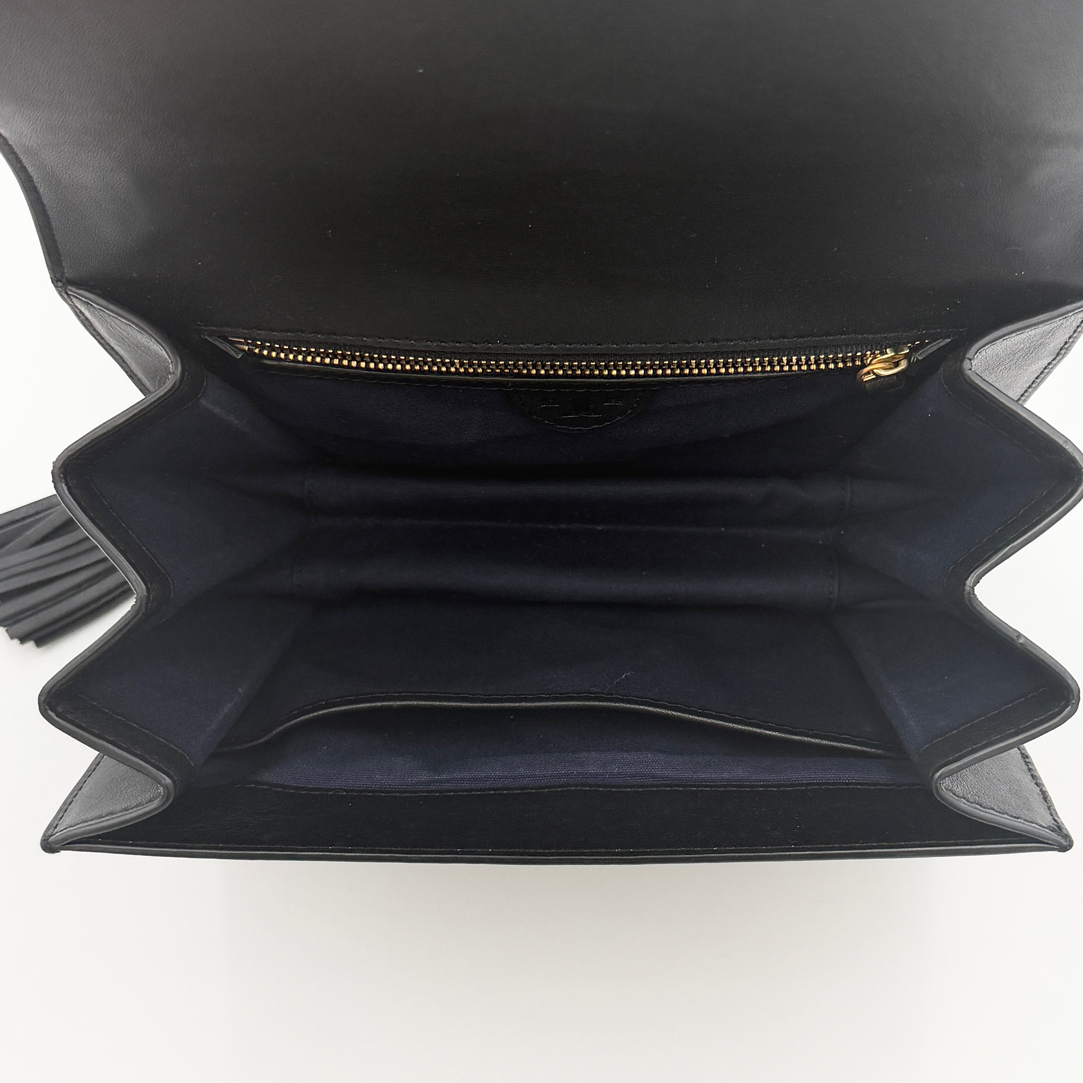 Tory Burch Brooke Crossbody Bag in black leather with gold-tone logo and a braided chain strap, elegantly displayed against a white backdrop.
