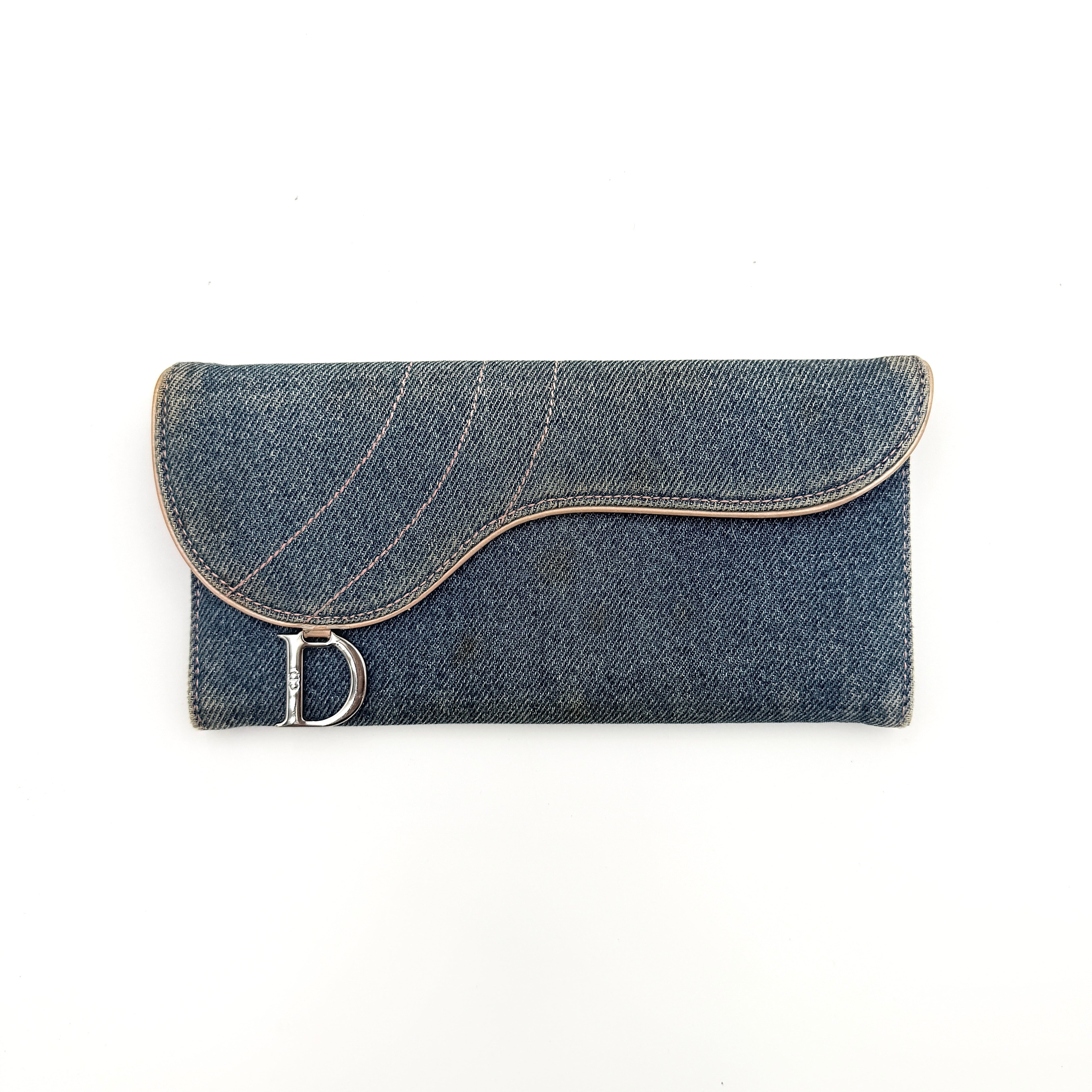 Dior Saddle Denim Wallet in blue denim with signature curved silhouette and silver-tone 'D' charm on the front flap.