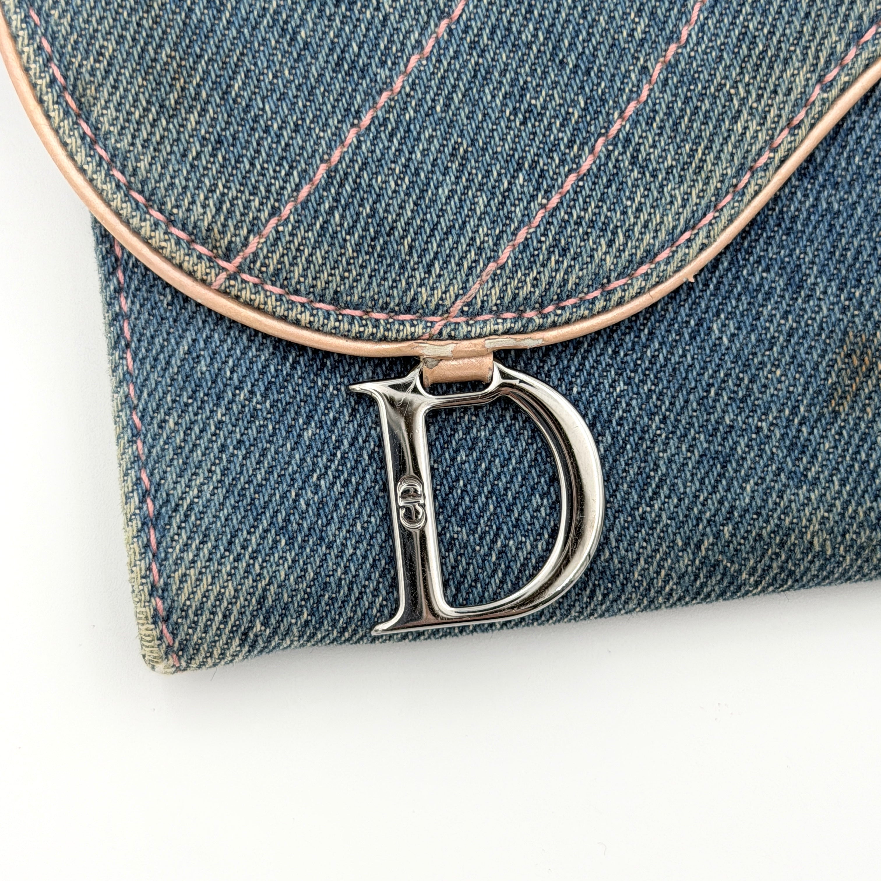 Dior Saddle Denim Wallet in blue denim with signature curved silhouette and silver-tone 'D' charm on the front flap.