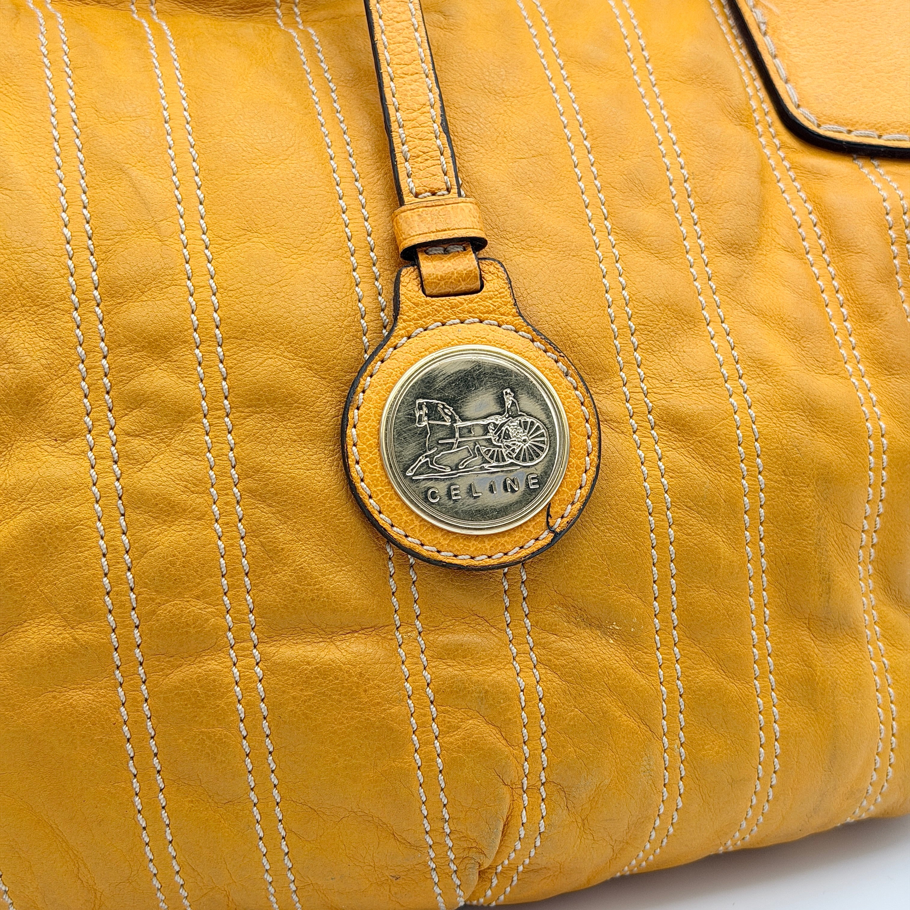 Celine Stripe Hobo Shoulder Bag in yellow leather with vertical stitching and signature gold-tone medallion, shown with dual handles.