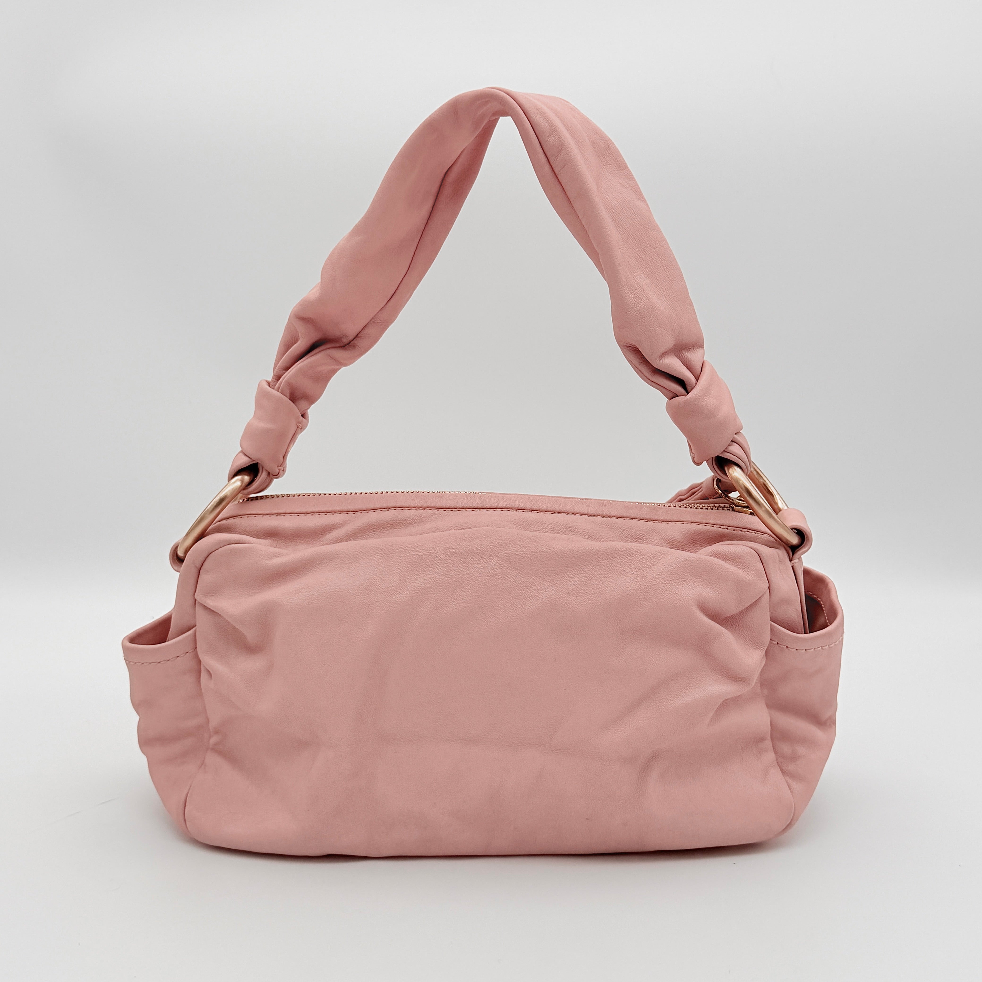 Coach pink leather hobo shoulder bag with knotted handle, gold-tone hardware, and side pockets.