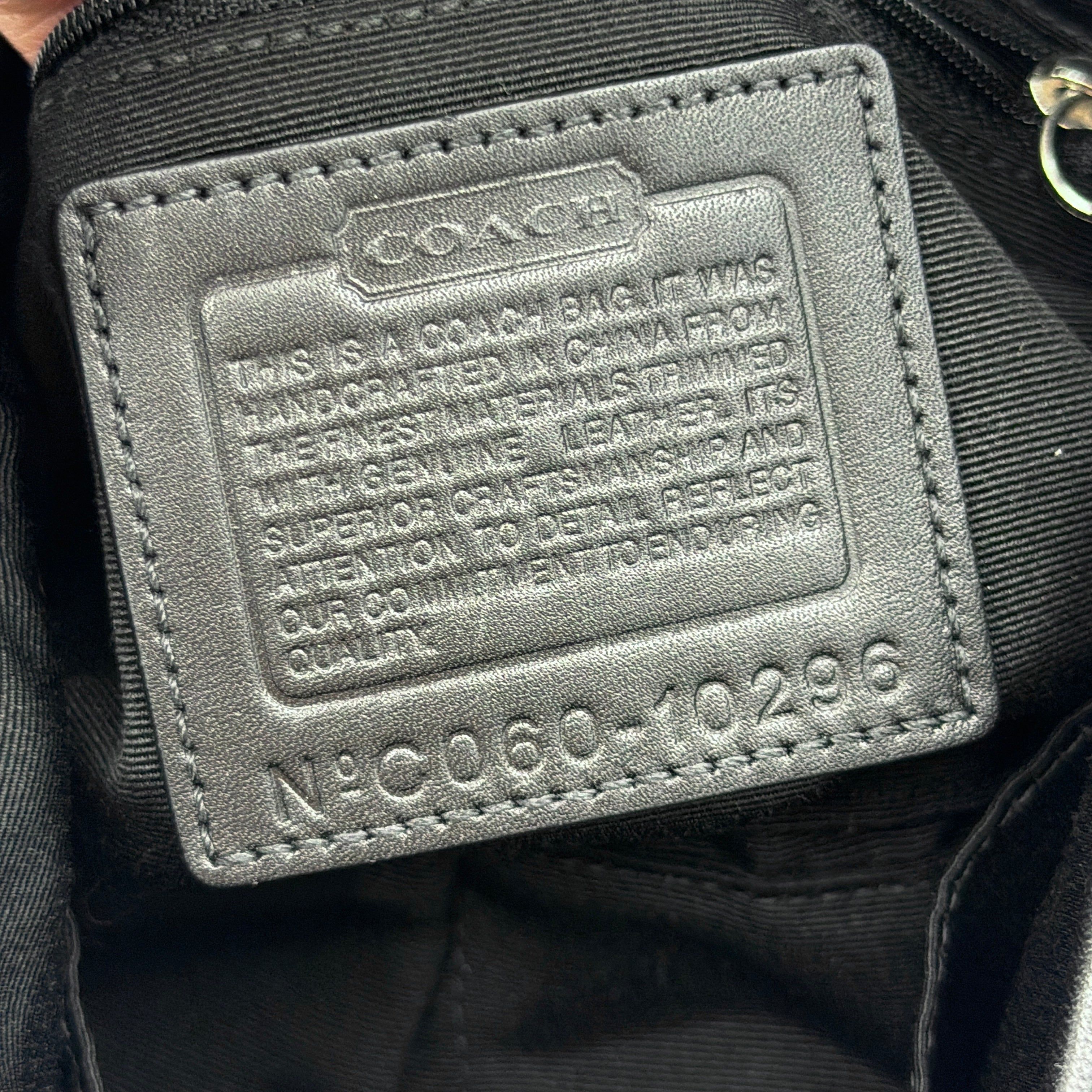 Coach black Signature Soho shoulder bag with oversized silver buckle, cream contrast stitching, and monogram jacquard canvas backdrop.