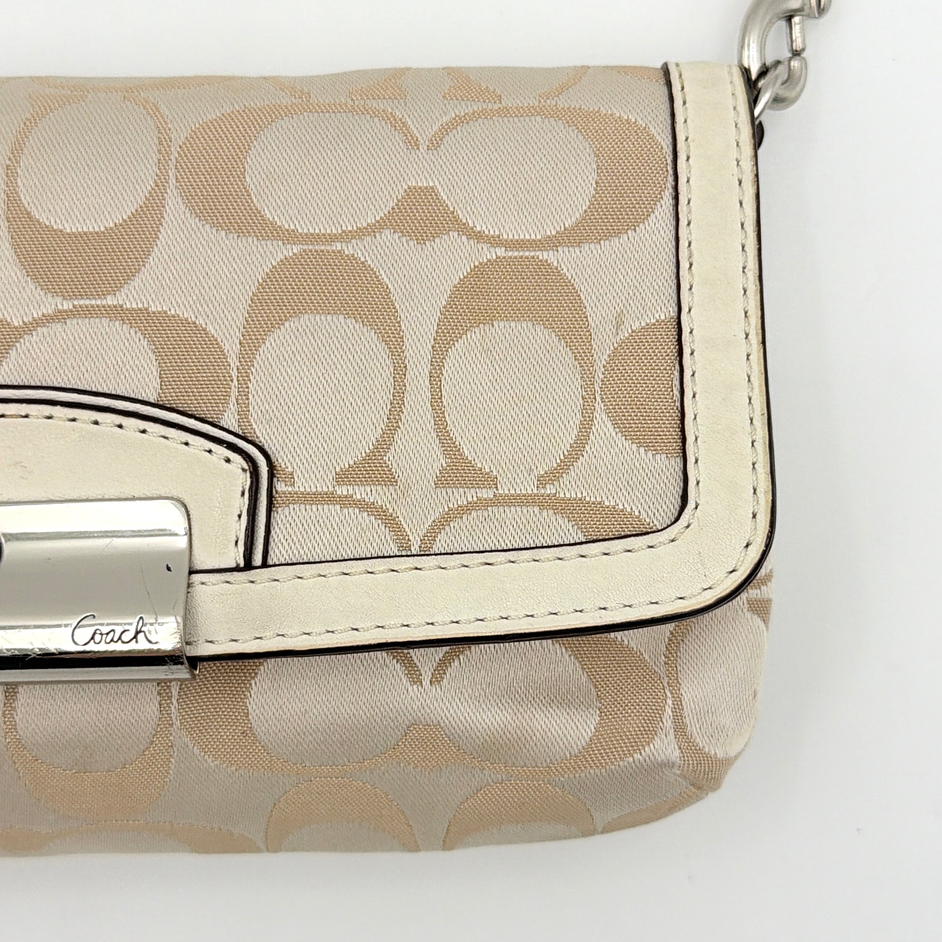 Coach Signature Kristin Shoulder Bag in beige and white jacquard canvas with white leather trim, presented with a polished silver push-lock clasp.