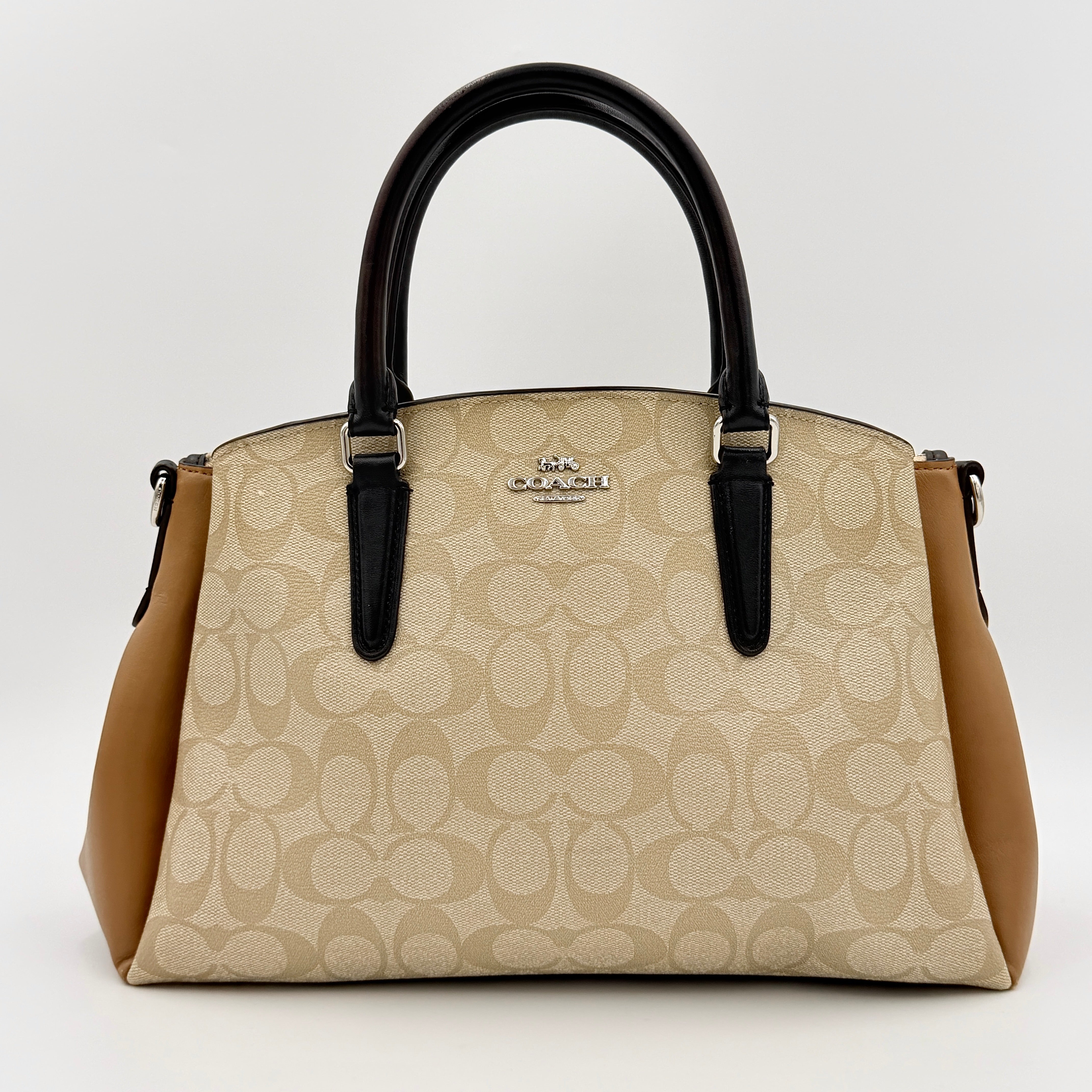 Coach Signature Sage Carryall in beige monogram canvas and tan leather with black handles, styled as an elegant, softly structured handbag.